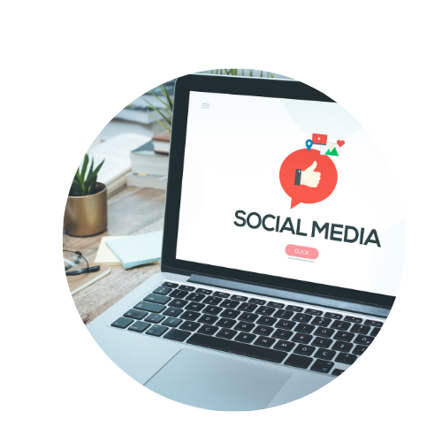 Open laptop displaying a social media icon and text on a desk with plants and notebooks