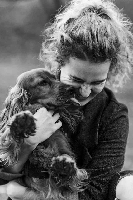 A woman hugging a dog with long ears and a shiny coat, both appearing happy and affectionate.