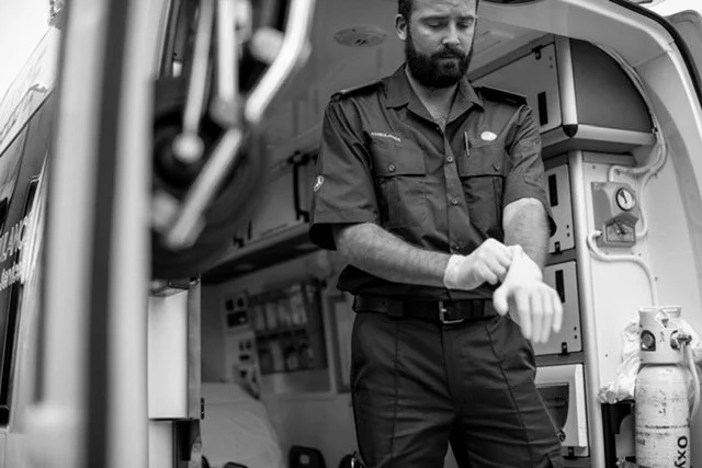 An emergency medical technician preparing to put on gloves inside an ambulance.