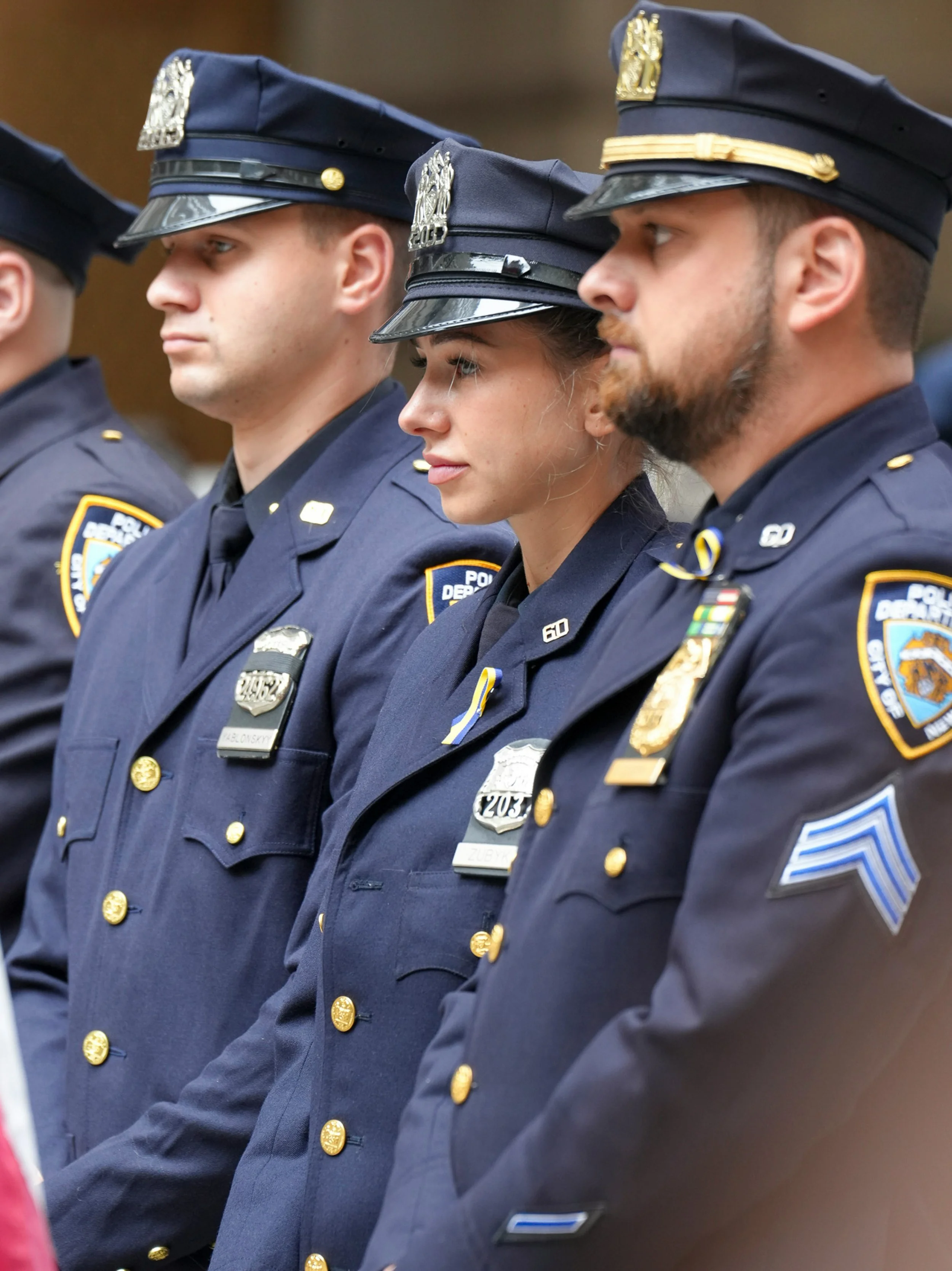 A sheriff officer wearing a uniform with "SHERIFF" on the back, standing outdoors during sunset.