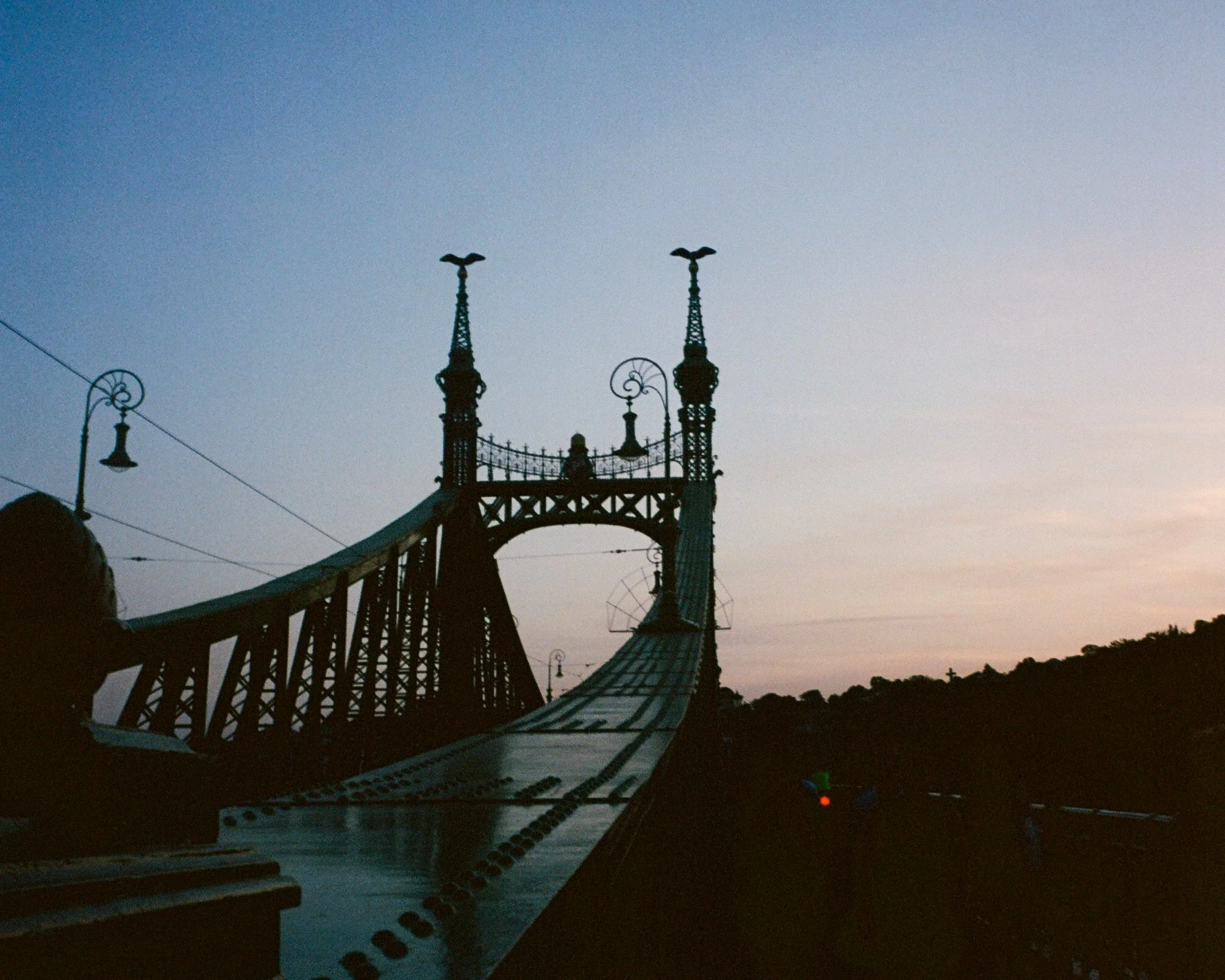 Silhouette du pont de Budapest contre un ciel au coucher du soleil.