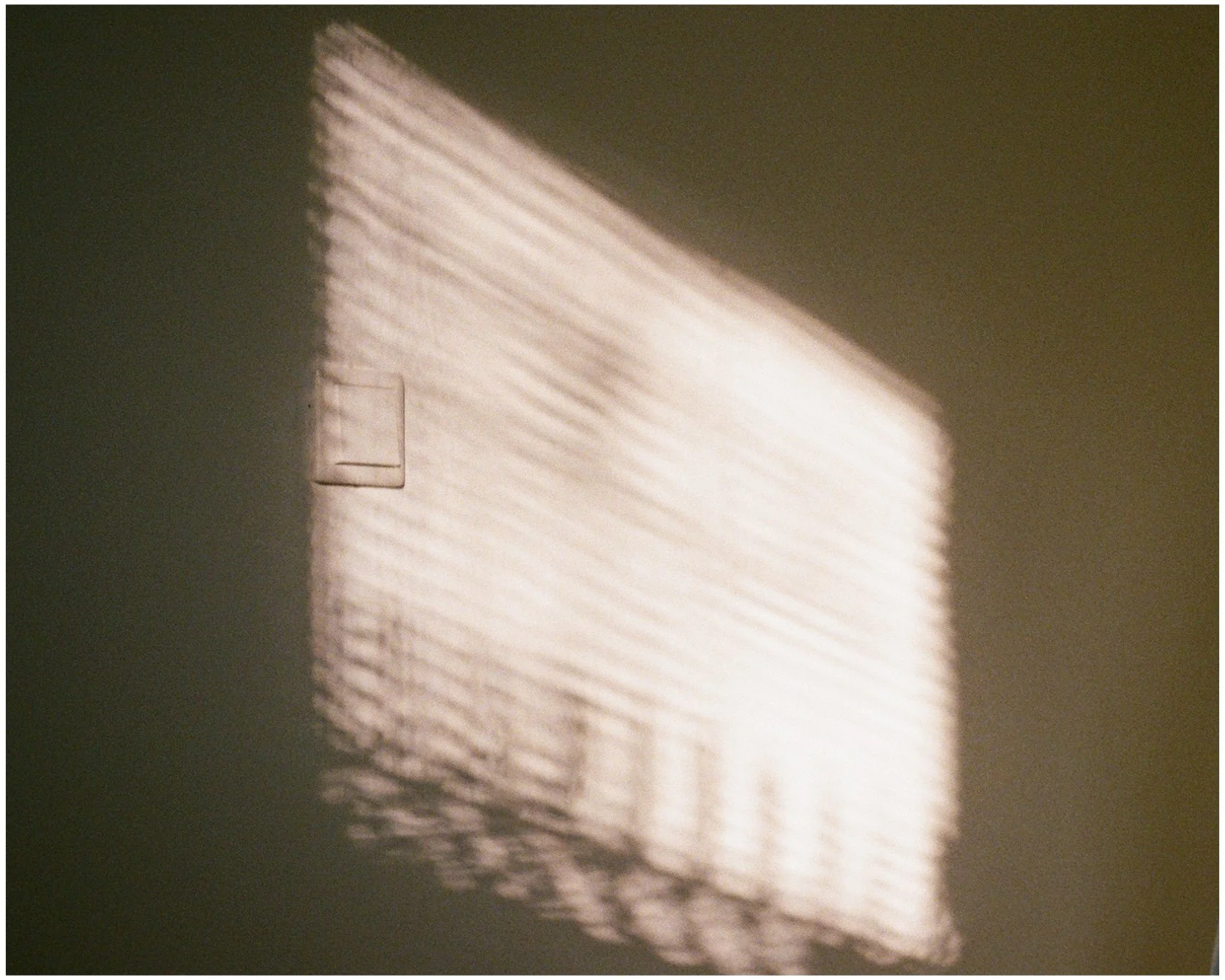 Reflet de lumière à travers des volets ou stores en miniature projetant des lignes lumineuses sur un mur