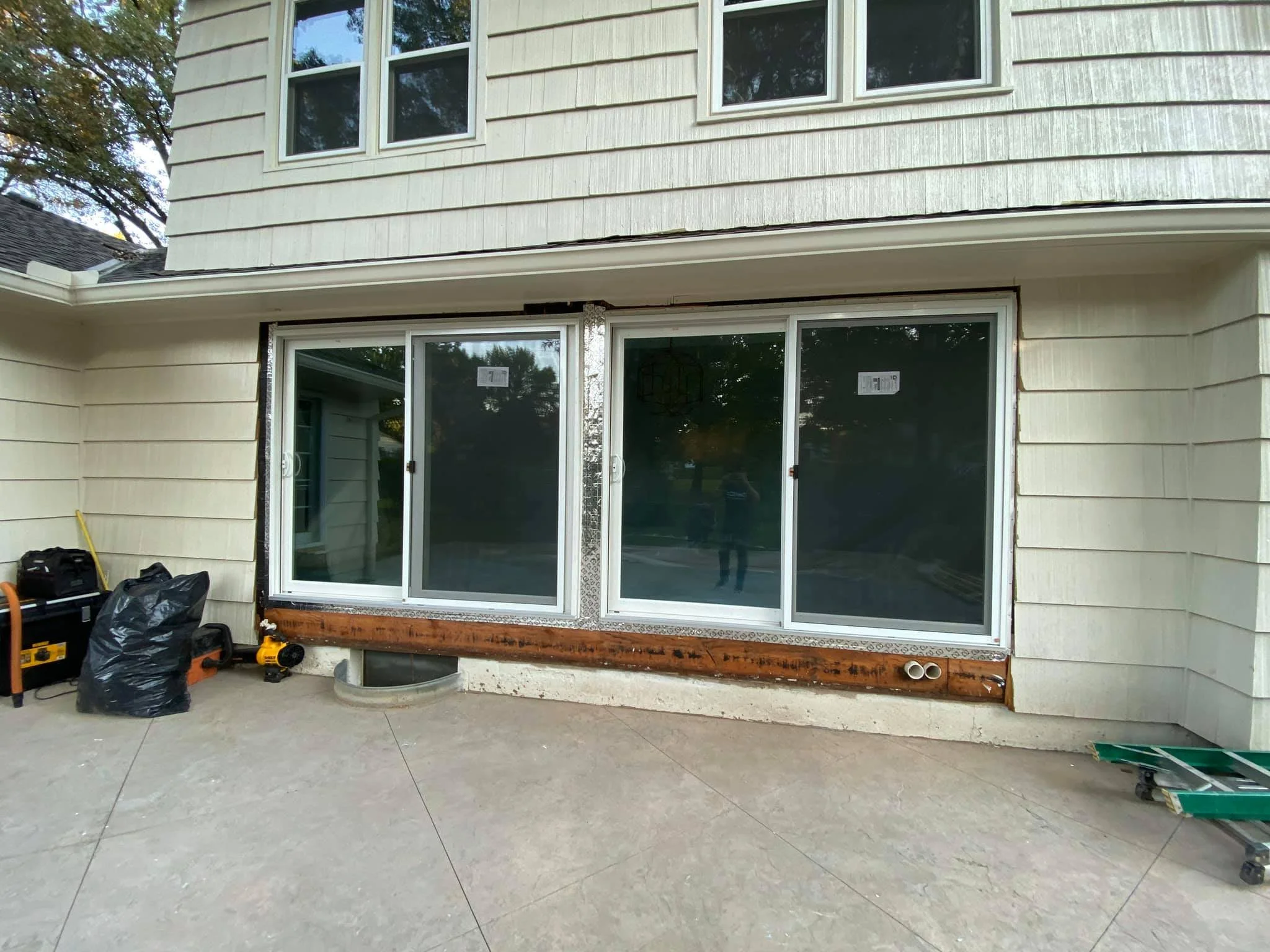 Back view of a house exterior with sliding glass doors, construction tools, and materials on the patio.