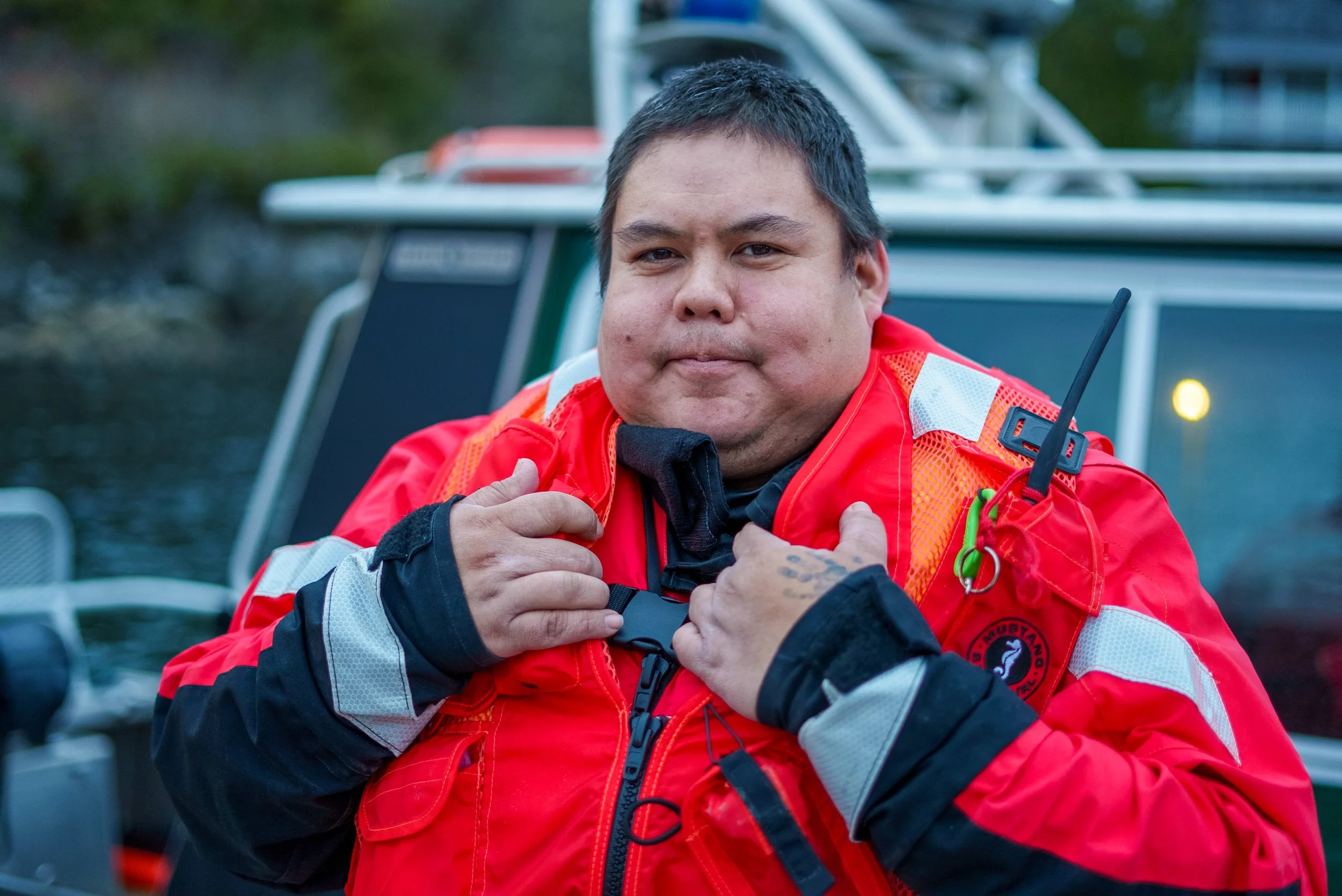 Man wearing a red rescue jacket, adjusting the collar.