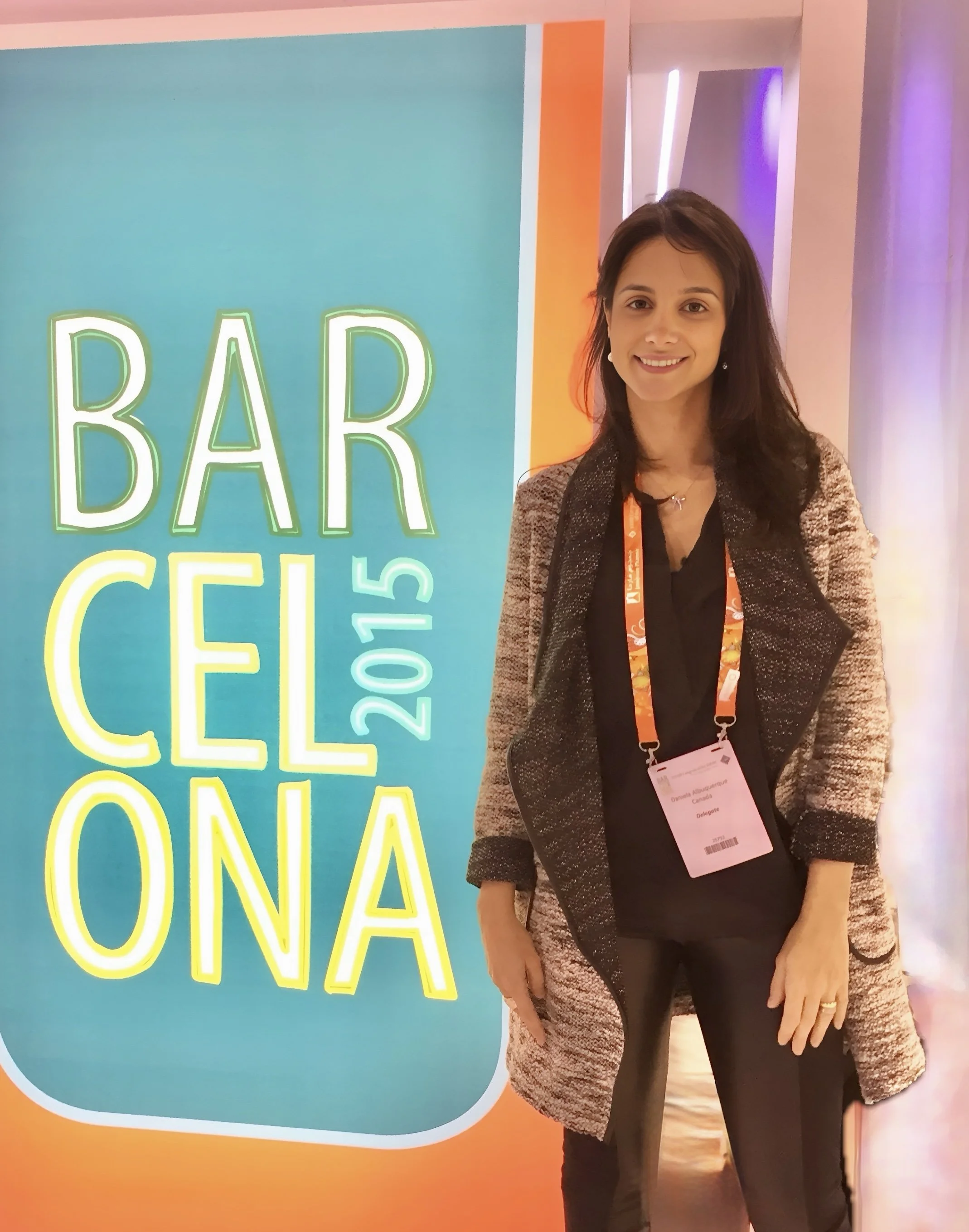 Dr. Daniela Albuquerque standing next to a colorful sign that reads 'Barcelona 2015' at ESCRS 2015.
