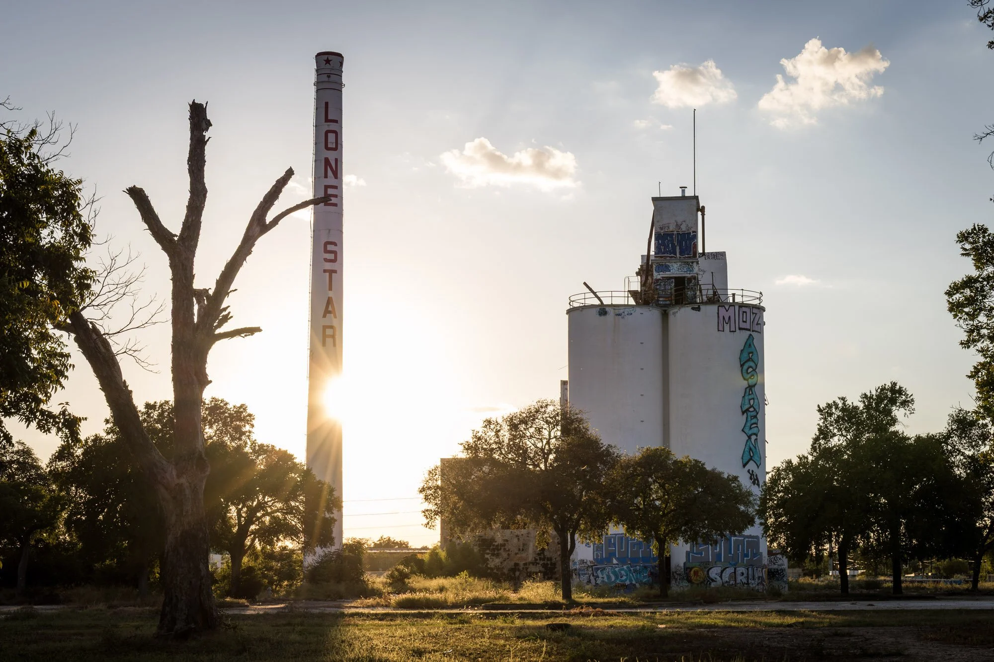 An abandoned industrial site with a tall smokestack that has 