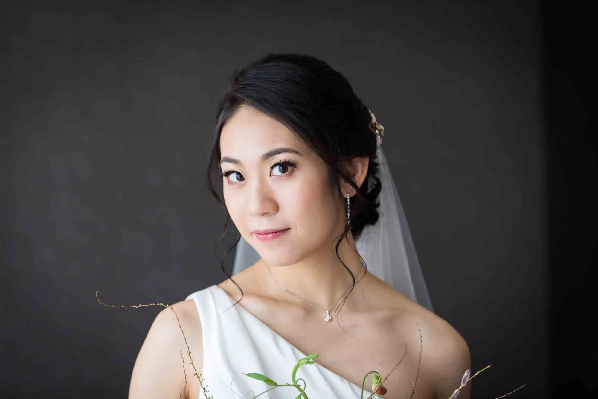 Asian American bride with hair up wearing one-shoulder dress and veil as photographed by San Antonio wedding photographer, Kelly Williams