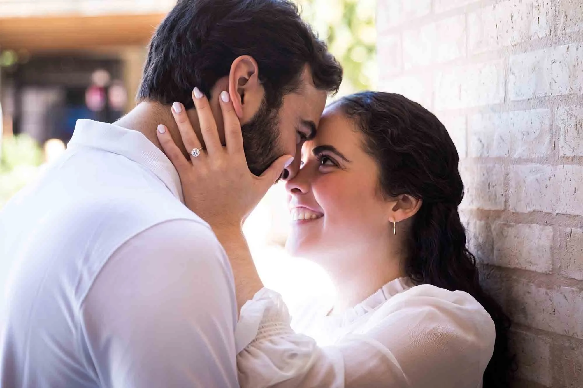 Woman holding man's face with her hand showing engagement ring, as photographed by San Antonio engagement photographer, Kelly Williams