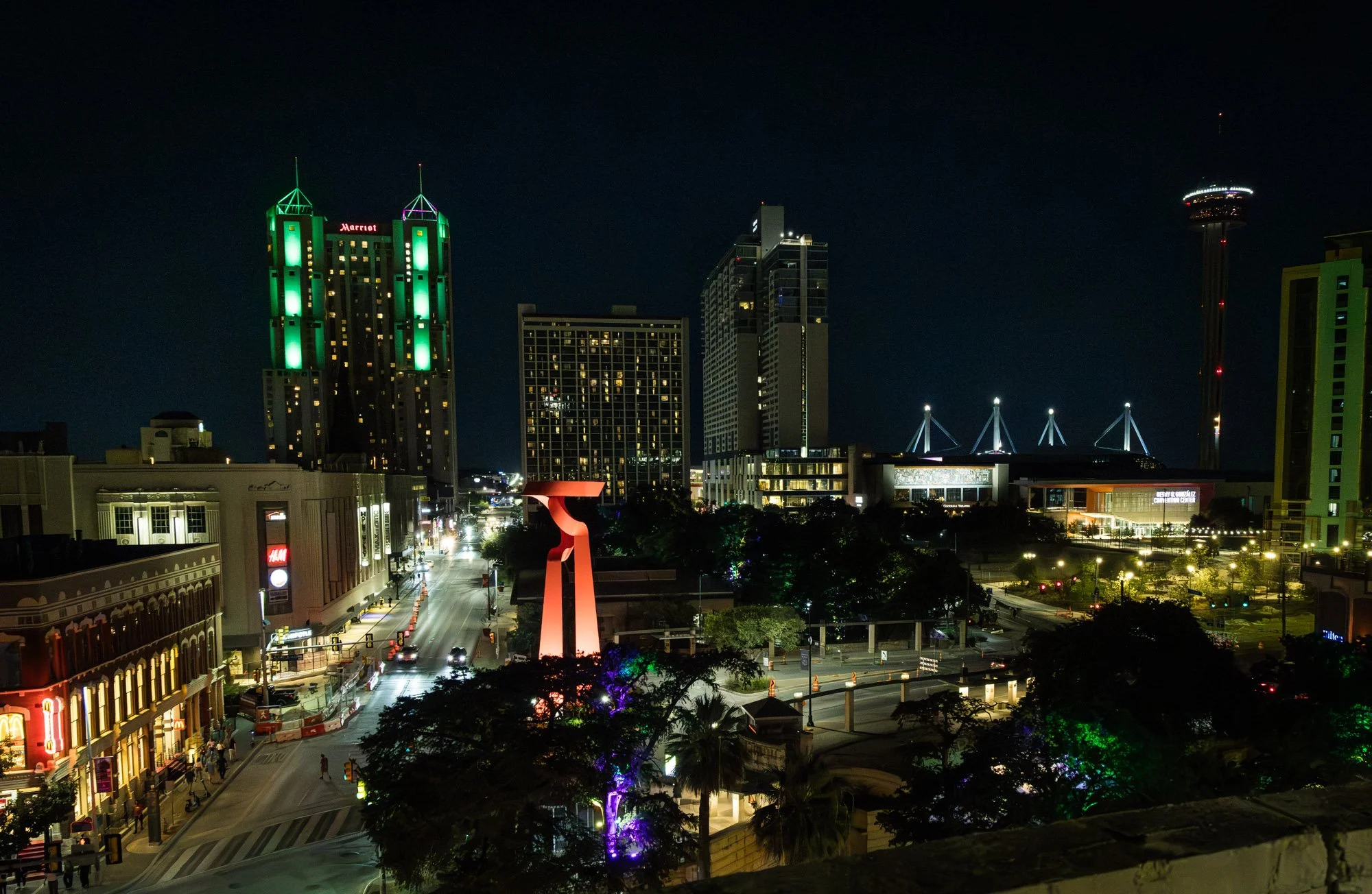 Night view of San Antonio downtown with illuminated buildings, Tree shaded street, and the Tower Life Building with green lights.