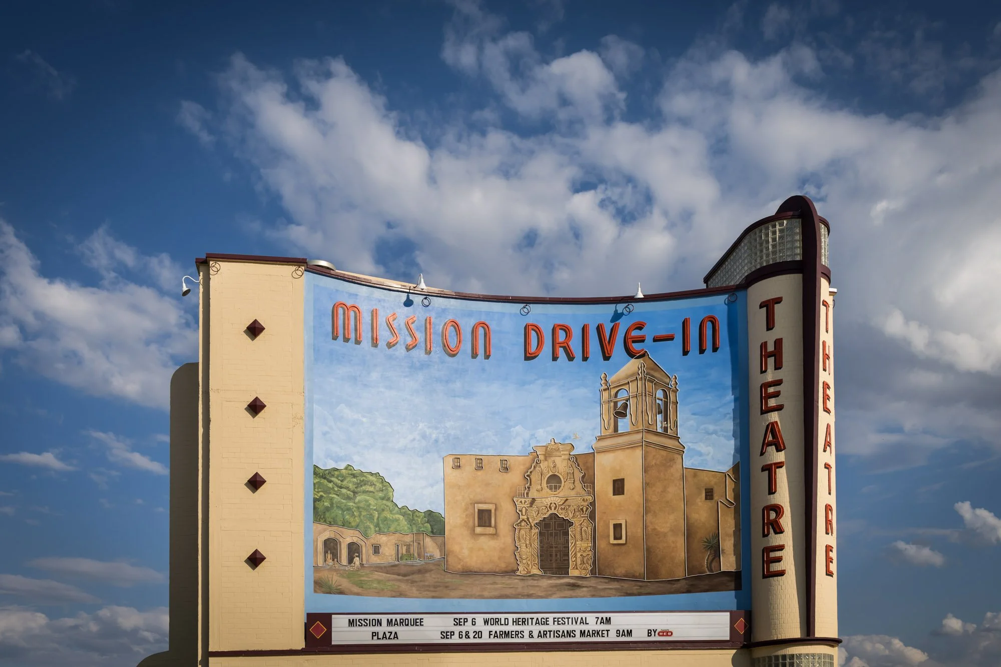 Sign for Mission Drive-In Theater with artwork of a historic building and event details at the bottom.