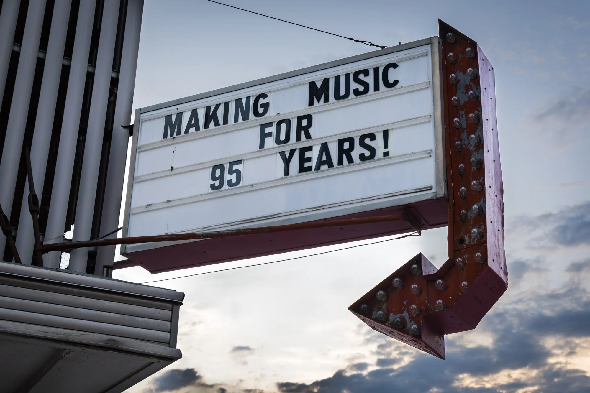 A marquee signs that reads 'Making Music for 95 Years!' against a cloudy sky.