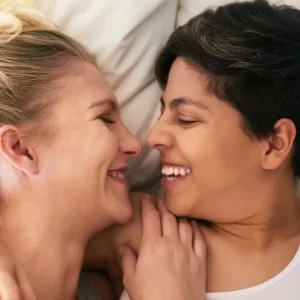 A happy couple lying close together, smiling and touching noses, in an intimate moment.