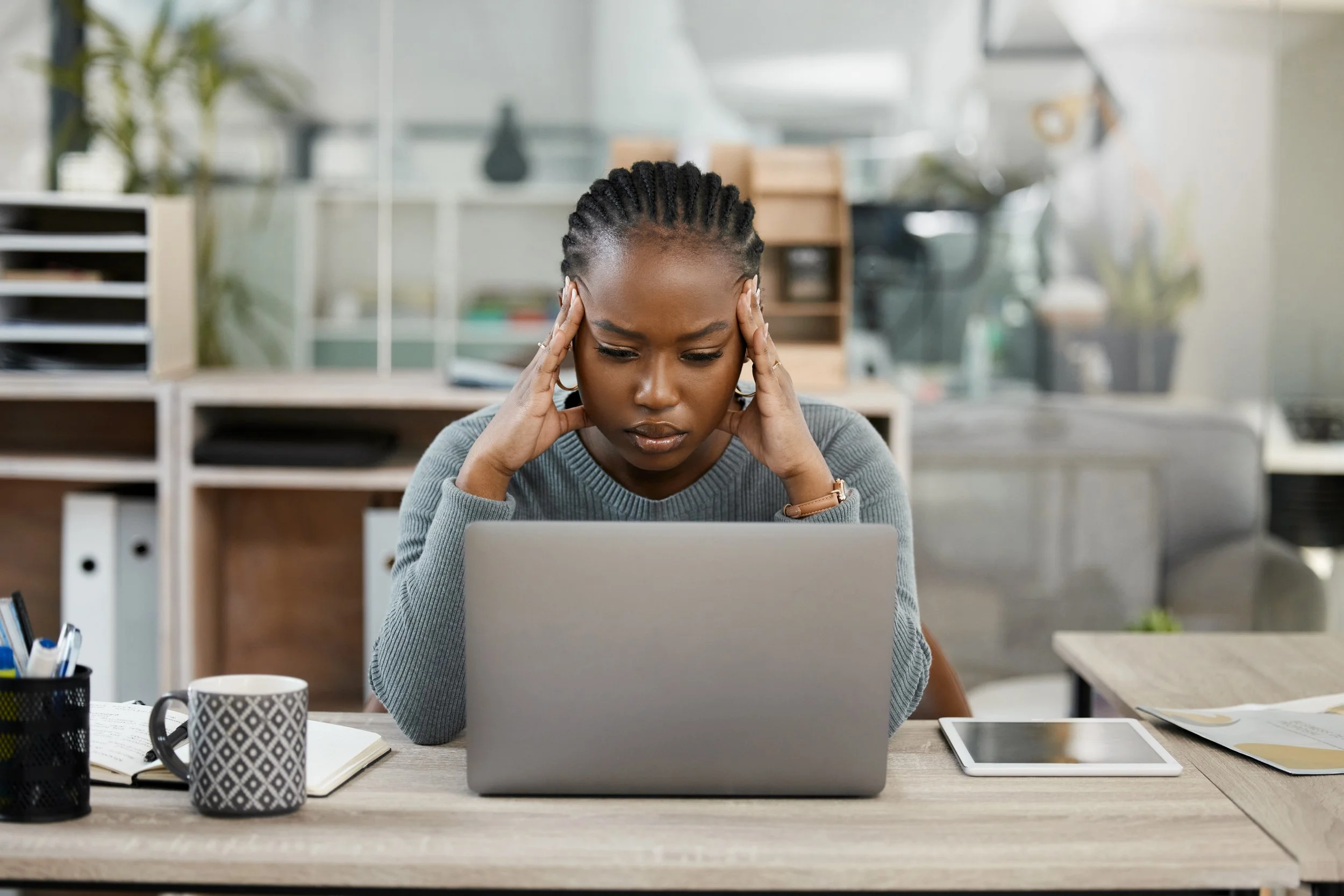 Business woman, laptop and headache in stress, burnout or depression in doubt, fail or mistake at office. Frustrated African female person or employee in anxiety or mental health problem at workplace