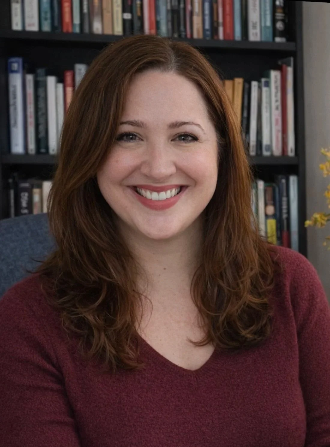 Dr. Dyan Connelly with brown hair a warm smile in front of a book shelf