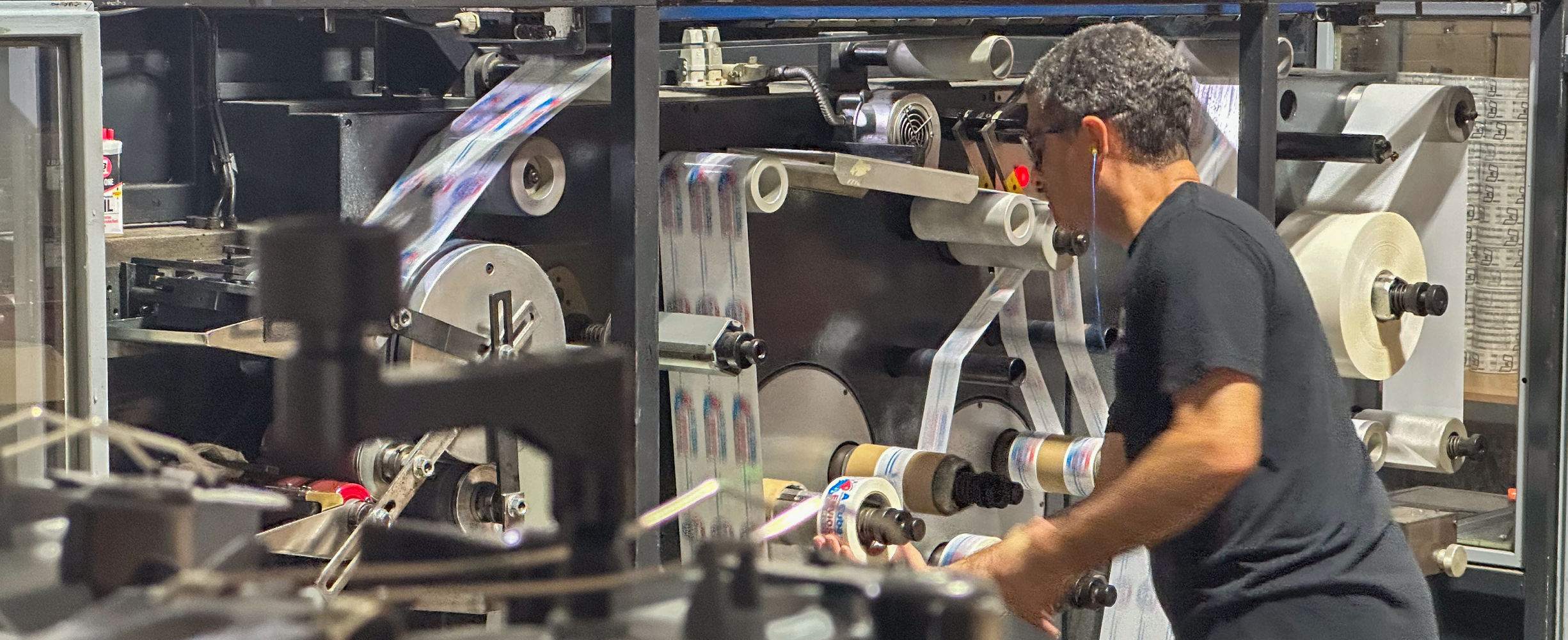 Person working on a printing press with rolls of printed material.