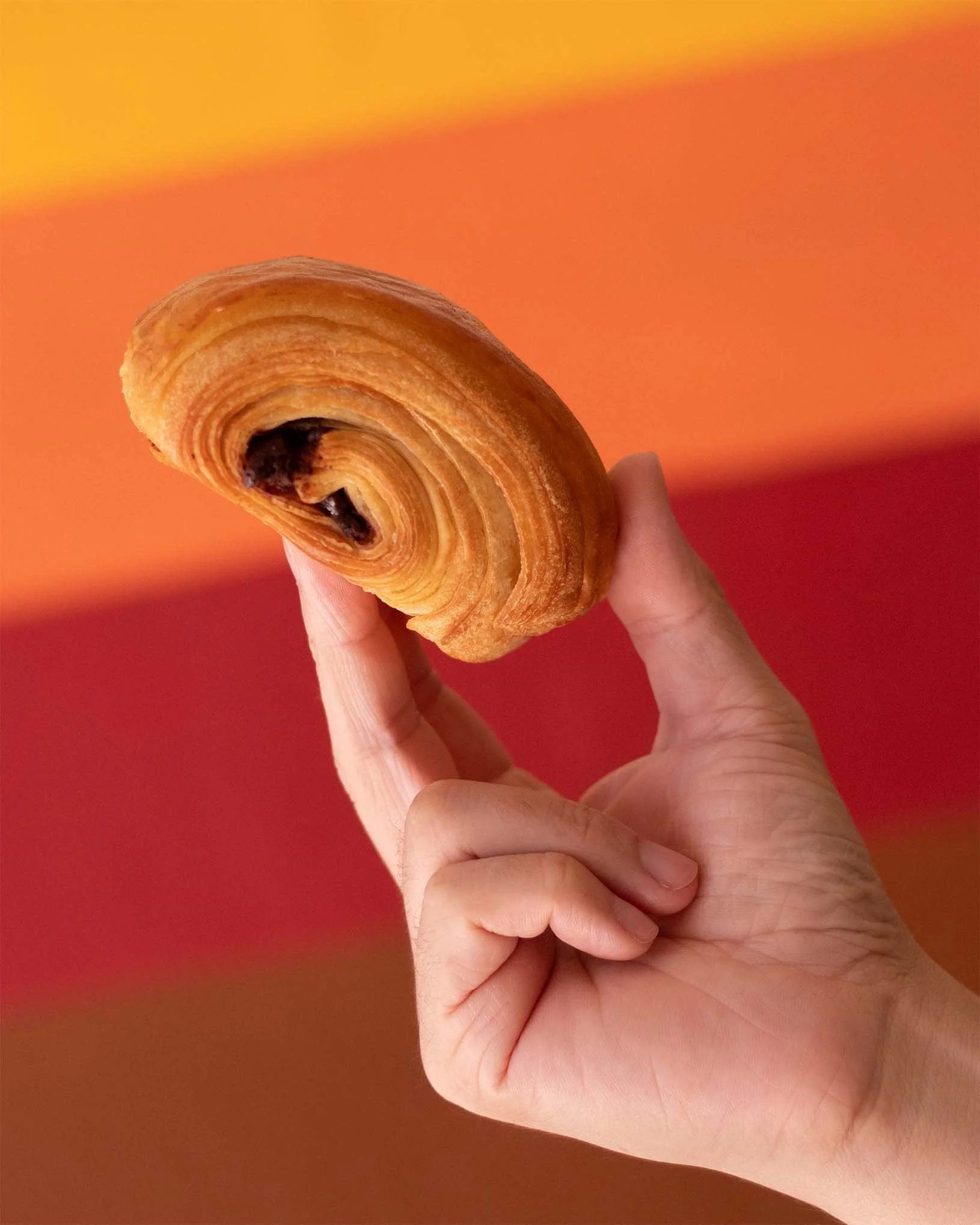 Fotografía de alimentos para campaña de Social Media. Mano sosteniendo un pan con relleno de chocolate.