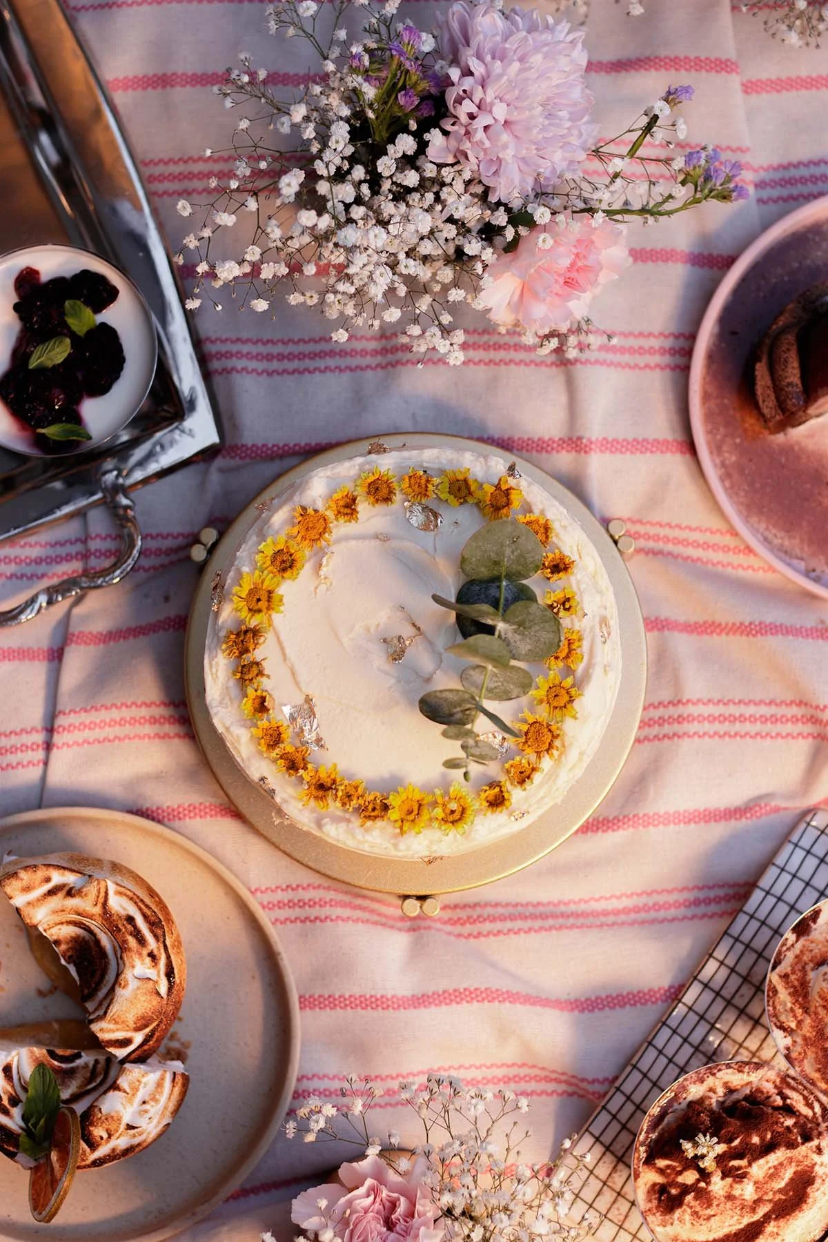 Fotografía de postres con iluminación natural del atardecer, al centro un pastel con decoración natural.