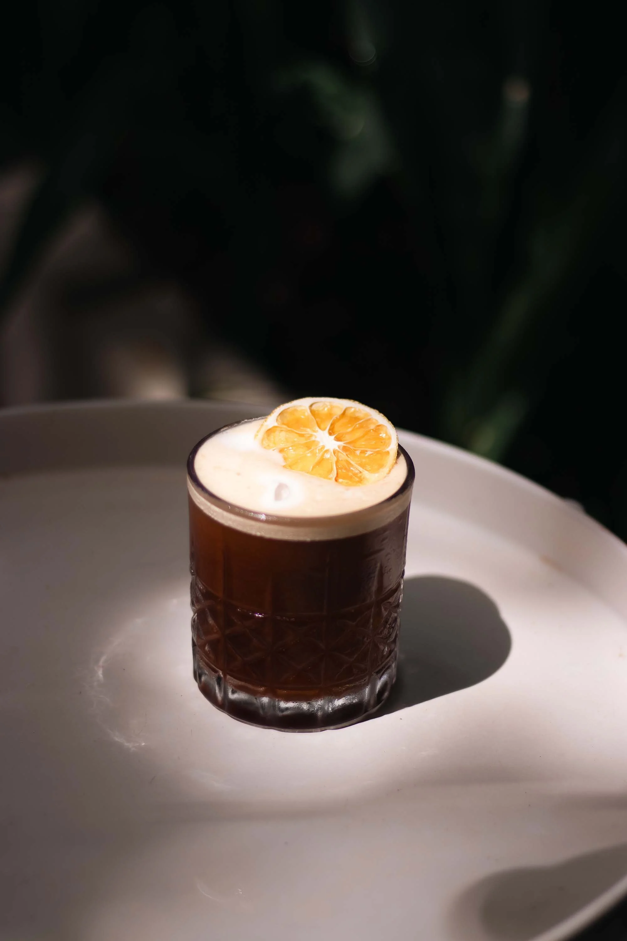 Fotografía de café frío, iluminada con luz natural del medio día que dibuja siluetas a través de la vegetación.