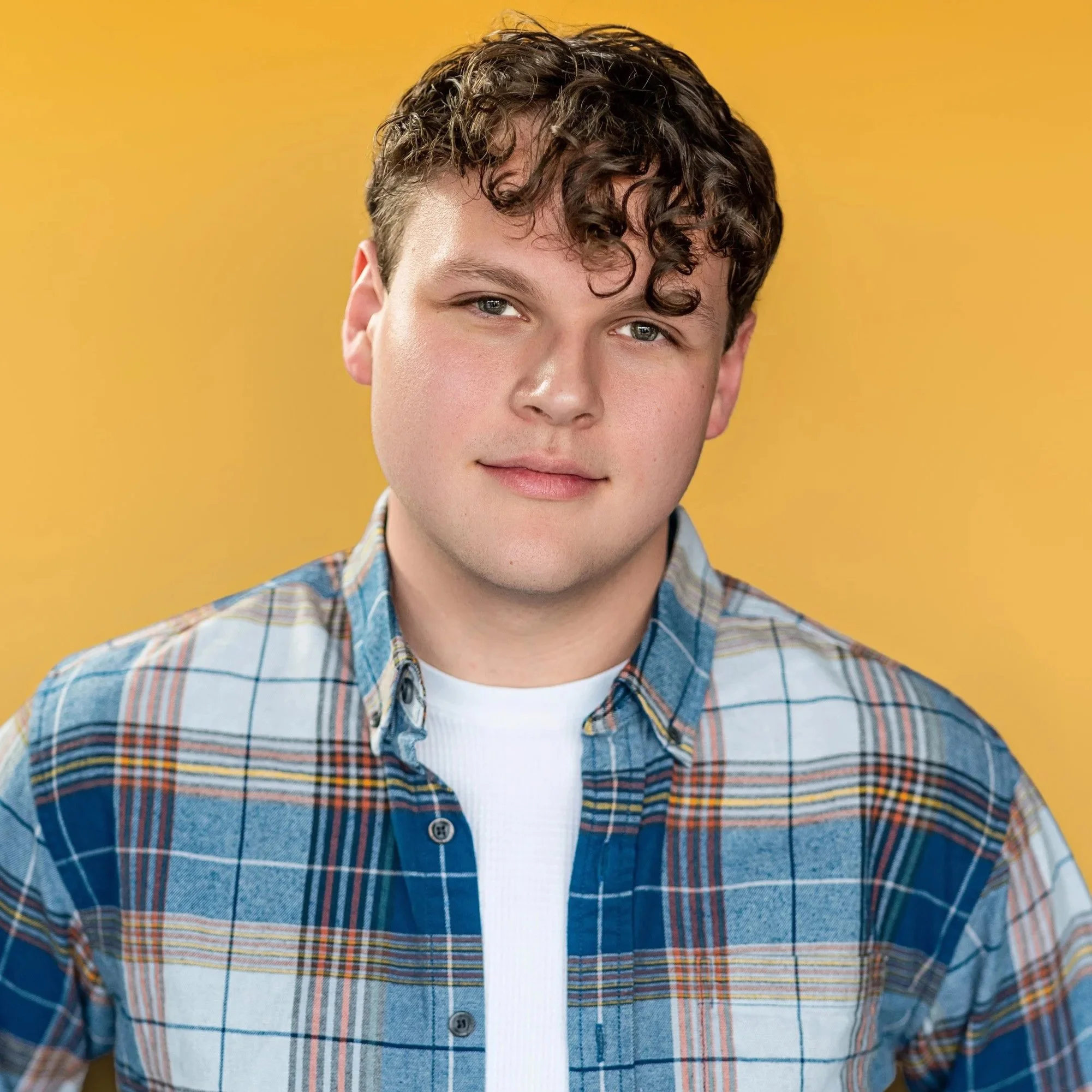 A theatrical stage performance with six actors, one standing on a tilted metal structure, holding a metal bar with women in vintage costumes pulling from opposite sides, under warm stage lighting.