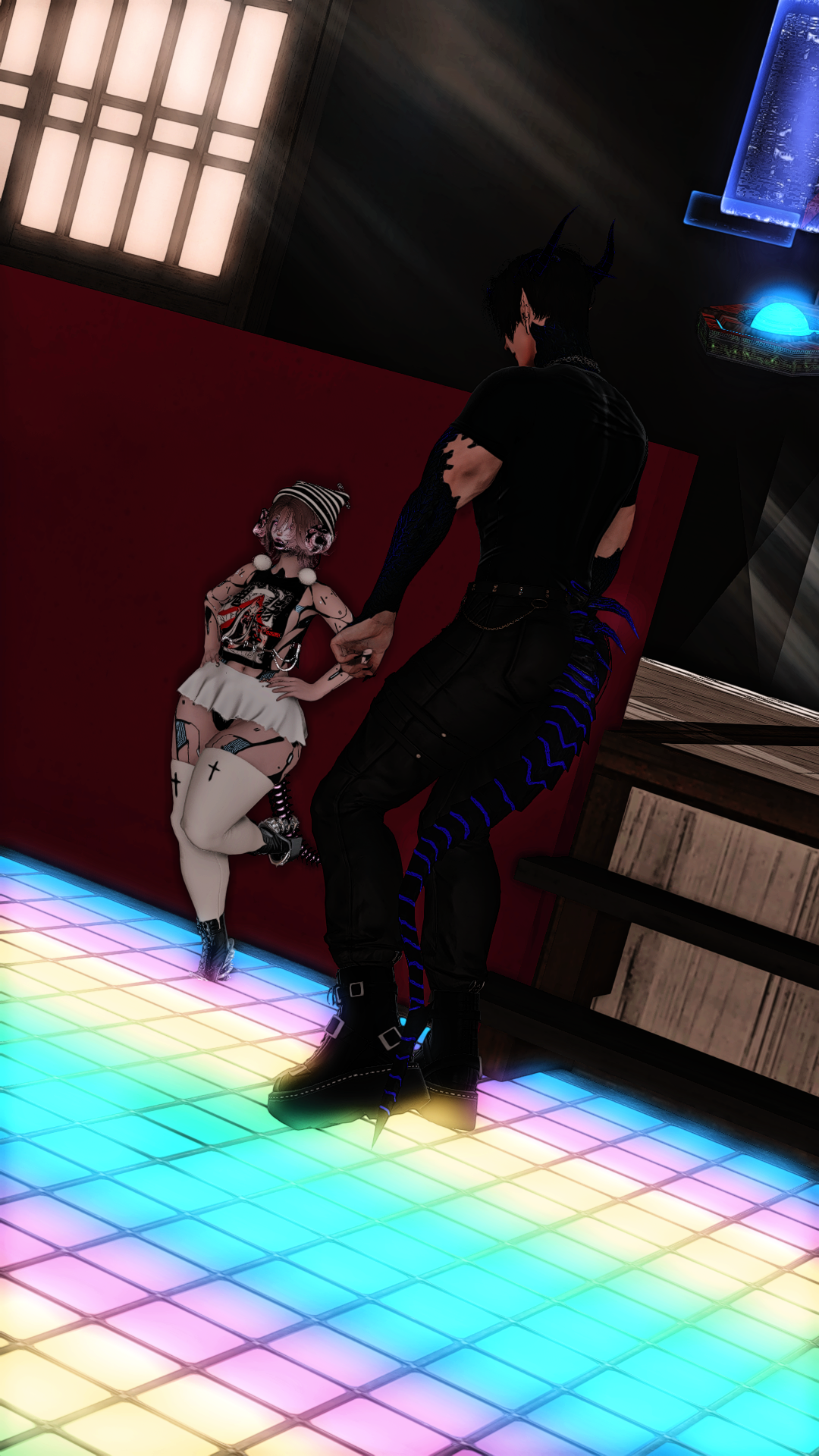 A person with black and blue striped tail and black horns holding hands with a girl dressed in Gothic Lolita fashion with a white skirt, black top with red accents, and white knee-high stockings, standing on a colorful LED-lit dance floor.