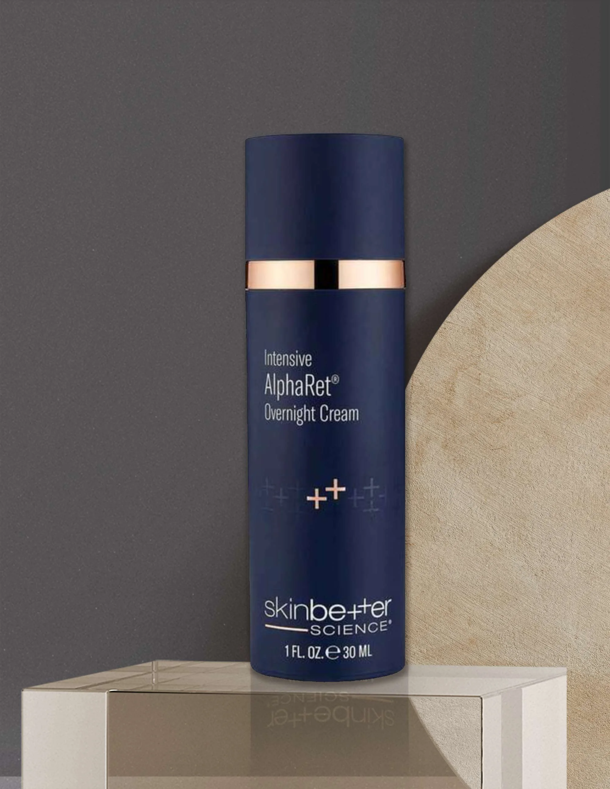 A bottle of SkinBetter Science Intensive AlphaRet Overnight Cream on a white pedestal, with a dark gray background and a curved wooden decor piece to the right.