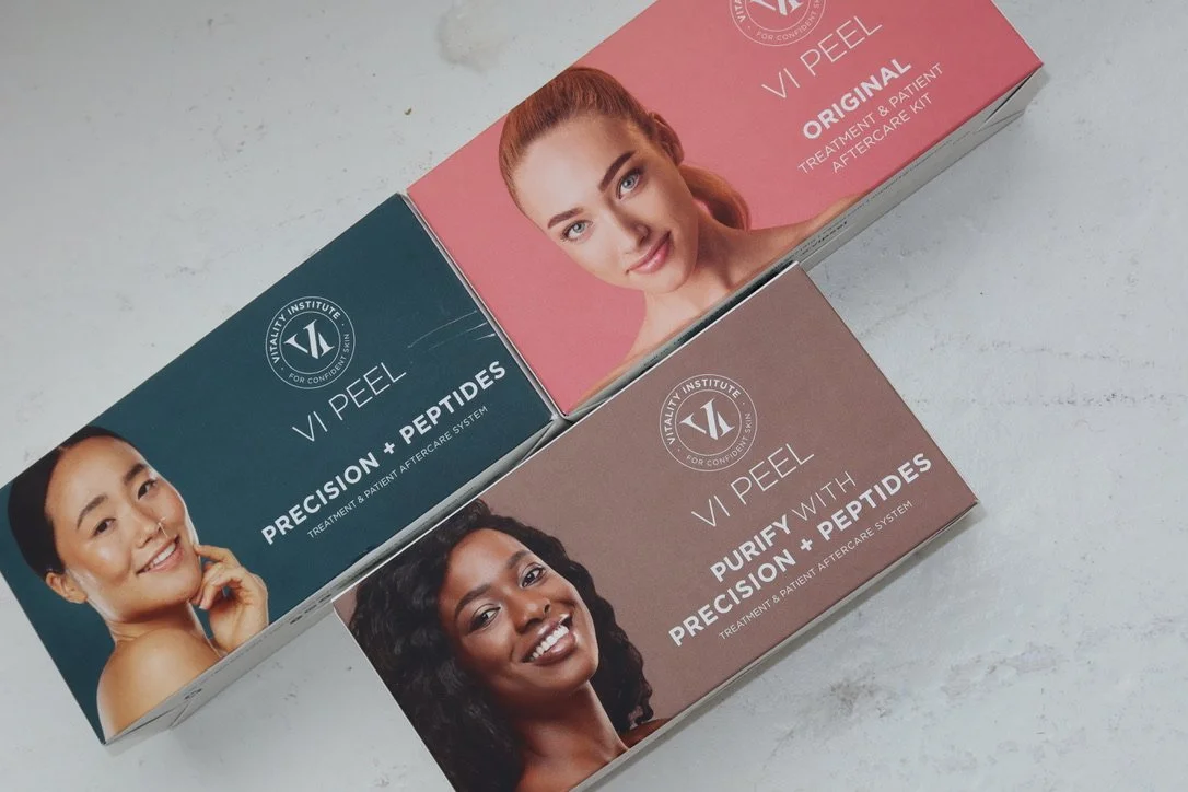 Three skincare products from Vitality Institute, labeled VI Peel, include Precision + Peptides, Original, and Purify with Peptides, arranged on a white surface.