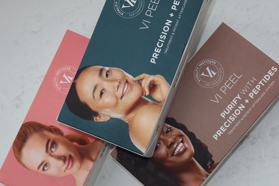 Three boxes of skincare products from the Vanity Institute, each featuring a woman's portrait with different skin tones, labeled as 'VIP Peel,' 'Purify with Peptides,' and 'Precision + Peptides.'