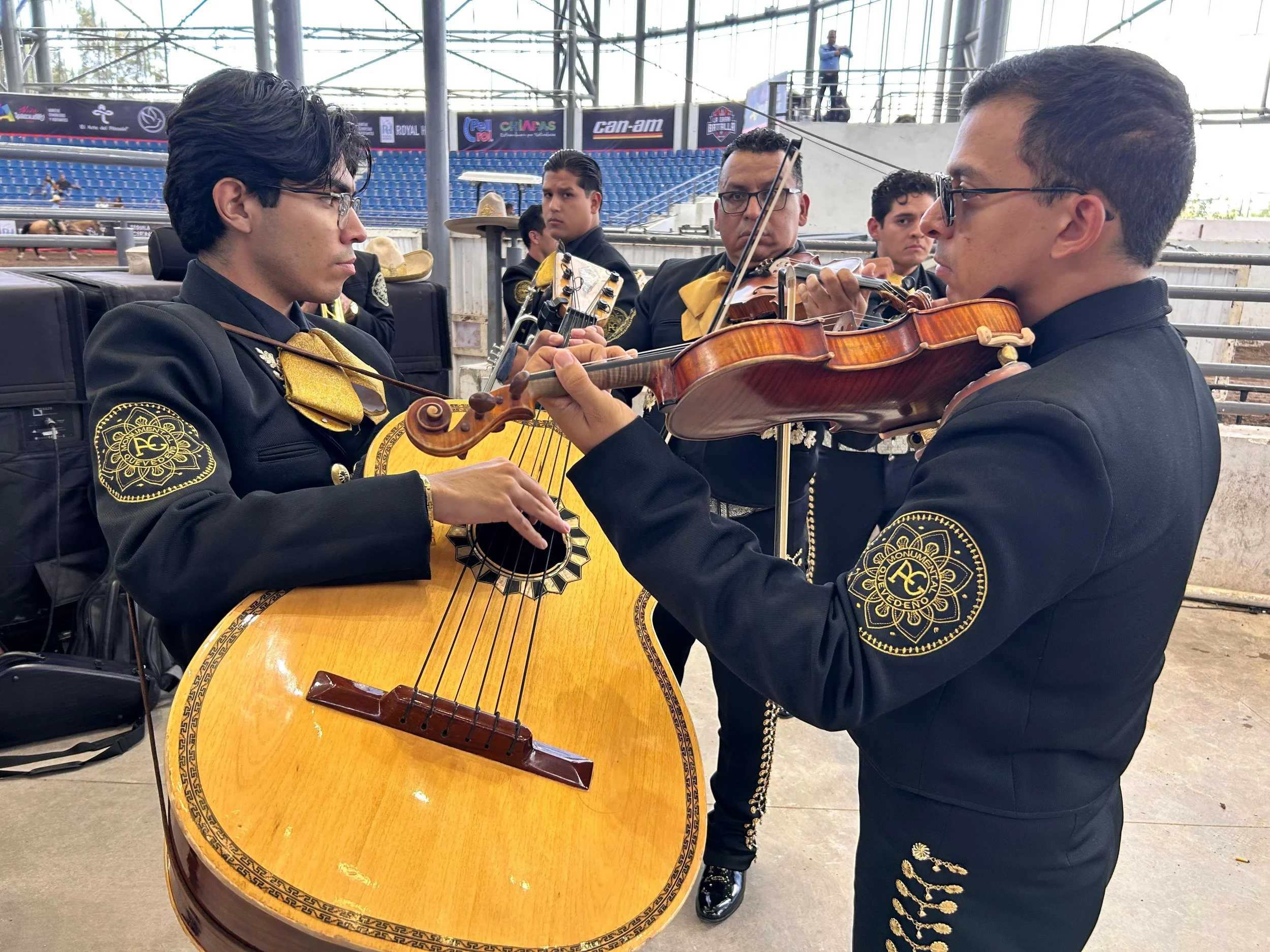 Grupo de músicos mexicanos de mariachi tocando instrumentos en un escenario al aire libre