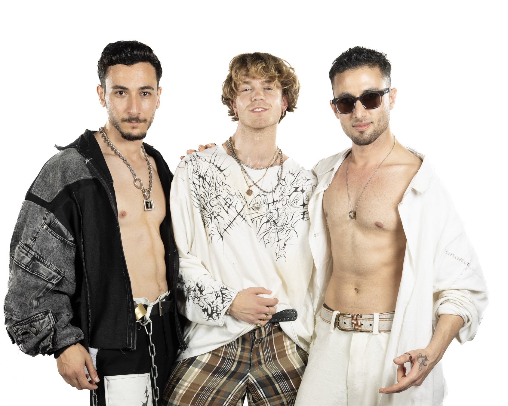 Three young men posing together against a white background, dressed in stylish, casual clothing with accessories like necklaces and sunglasses.