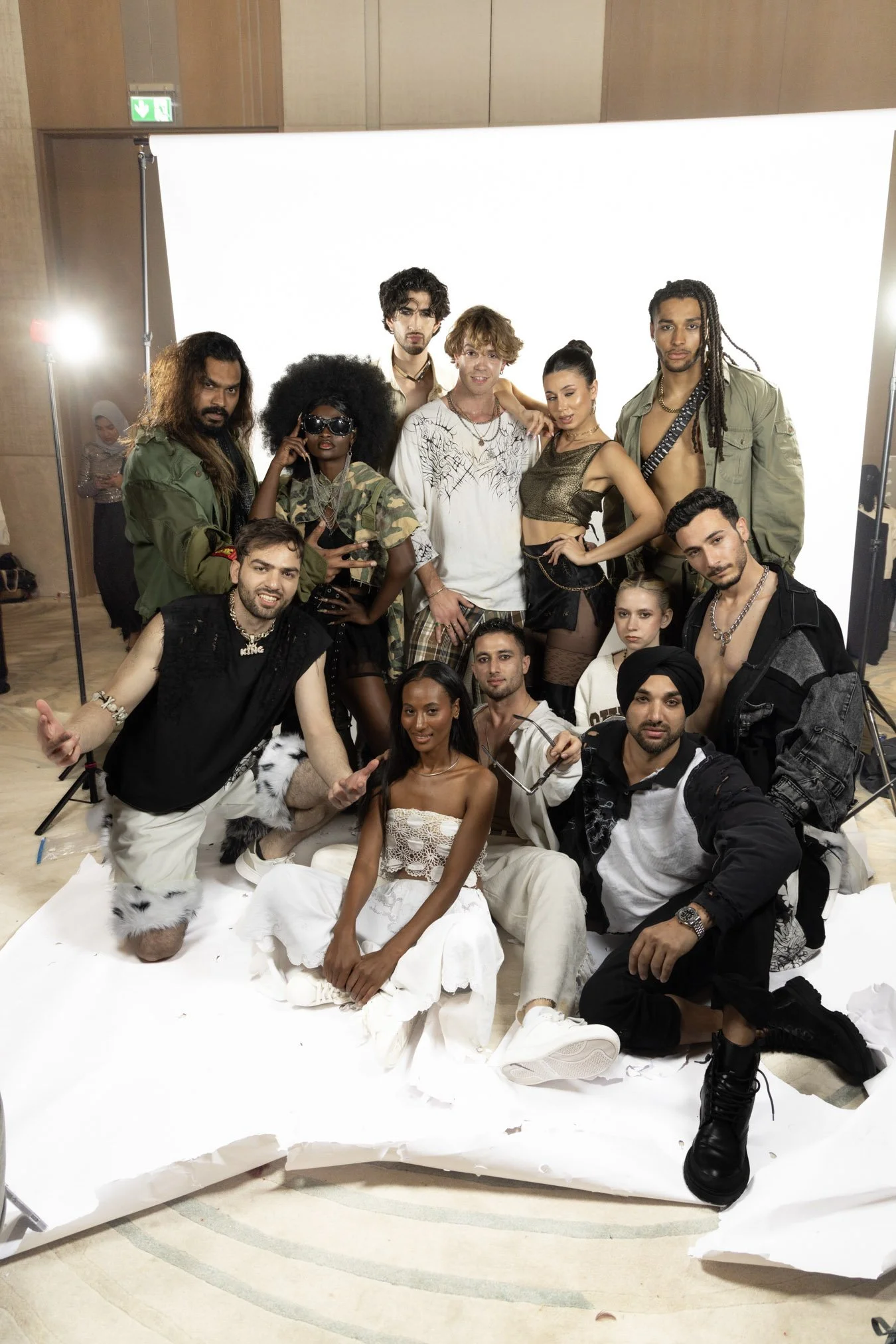 A diverse group of models posing together in front of a white backdrop at a photoshoot.