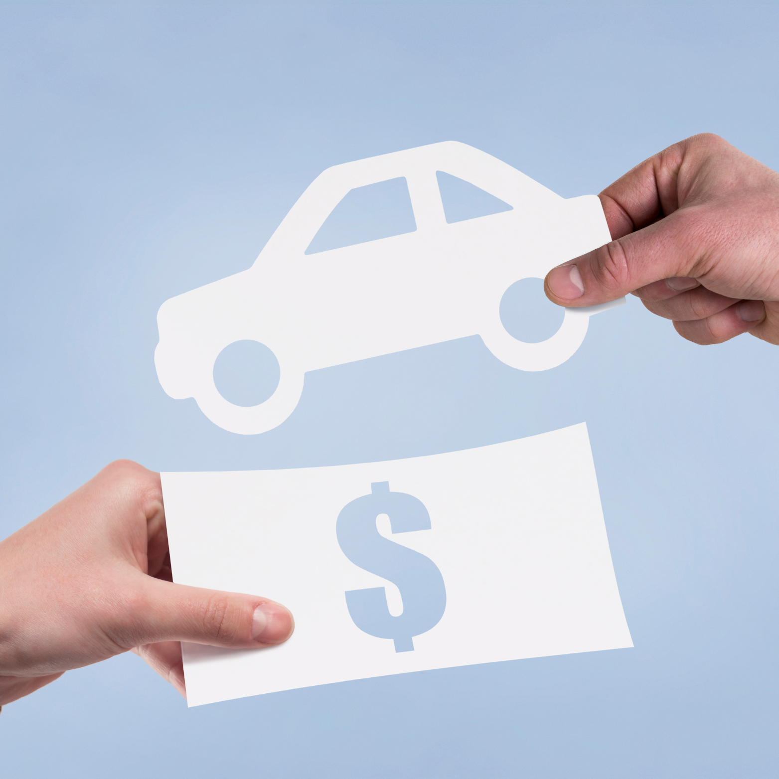 Two hands holding a paper cutout of a car above a paper with a dollar sign, symbolizing car financing or sale.