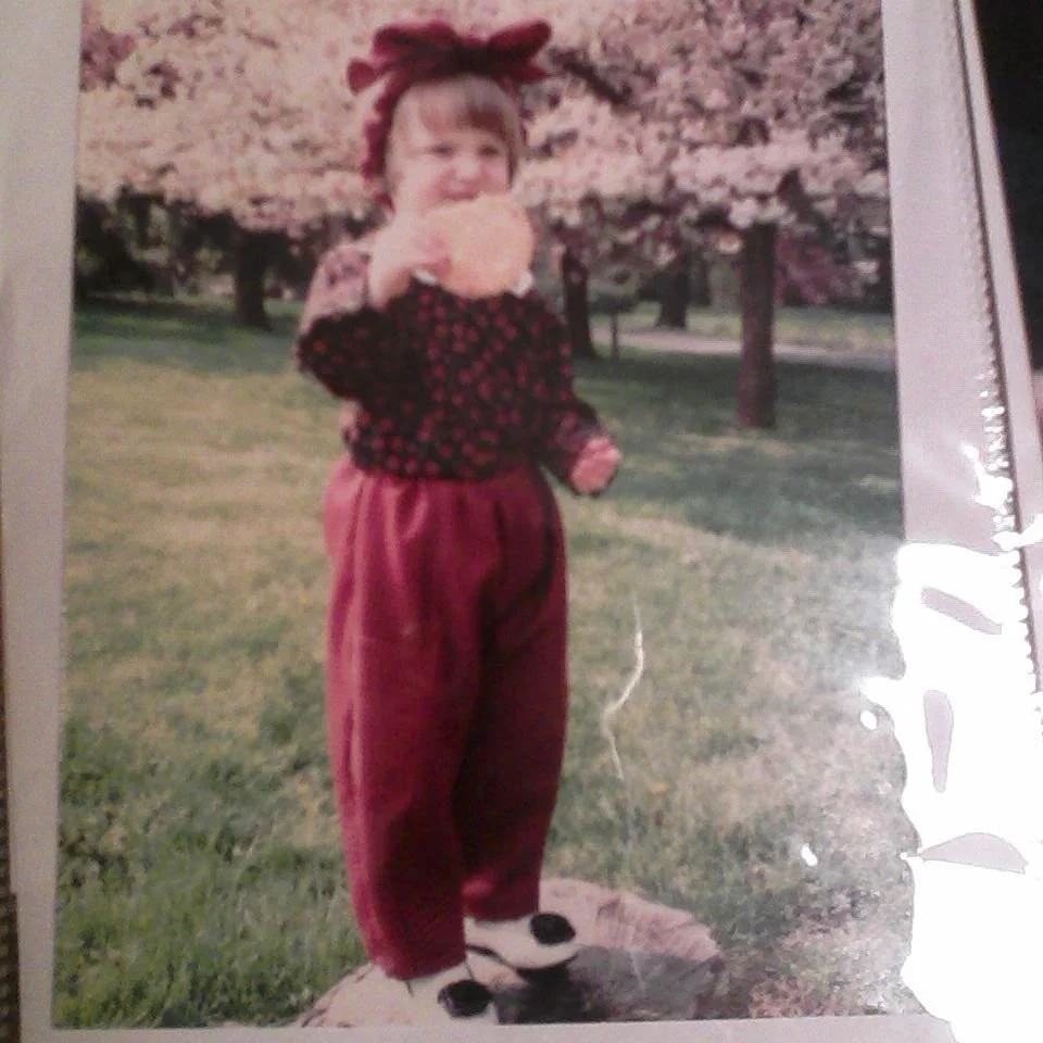 me as a kid witha giant bow and a bigger cookie with pom poms on my shoes
