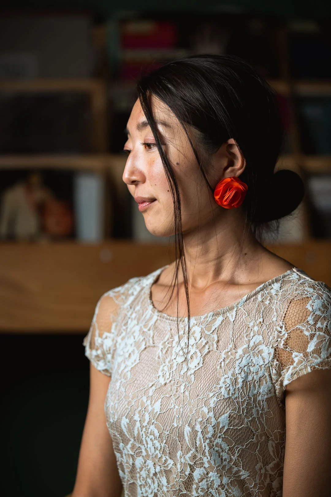 A woman with curly hair dancing in front of a lace curtain backdrop on a wooden floor.