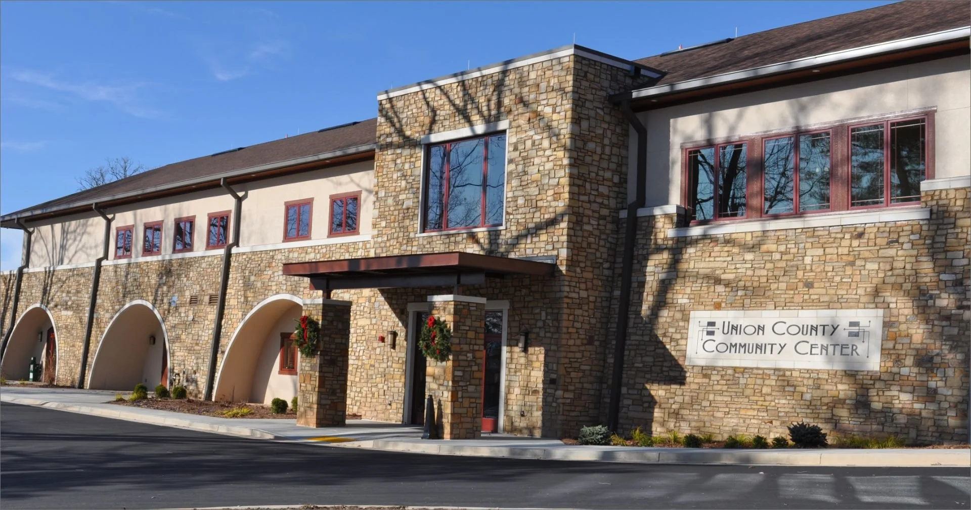 The building is the Union County Community Center with a brick and stone exterior, arched entryways, and festive holiday wreaths.