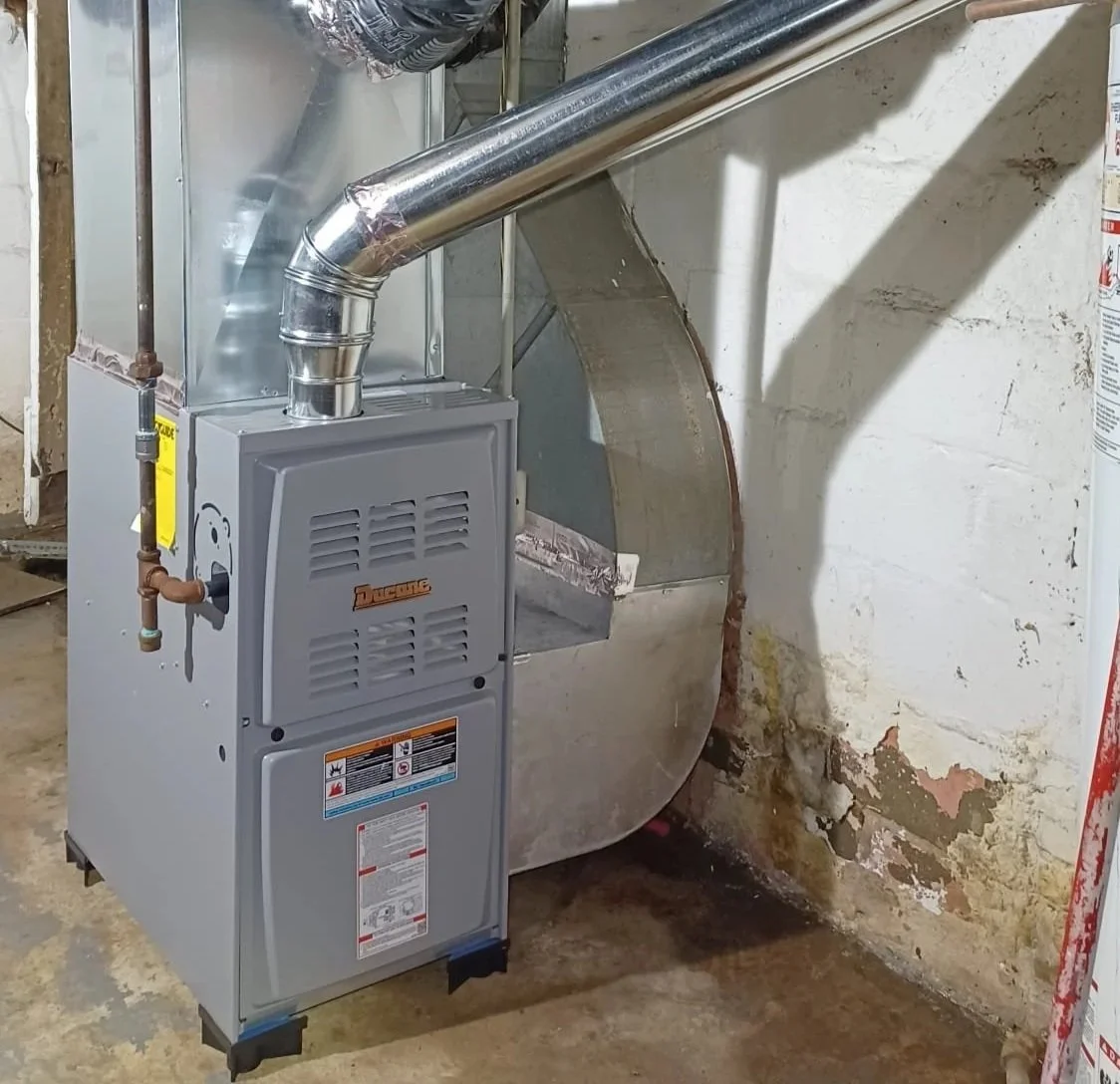 A ducane furnace unit installed in a basement with a ventilation duct connected to it.