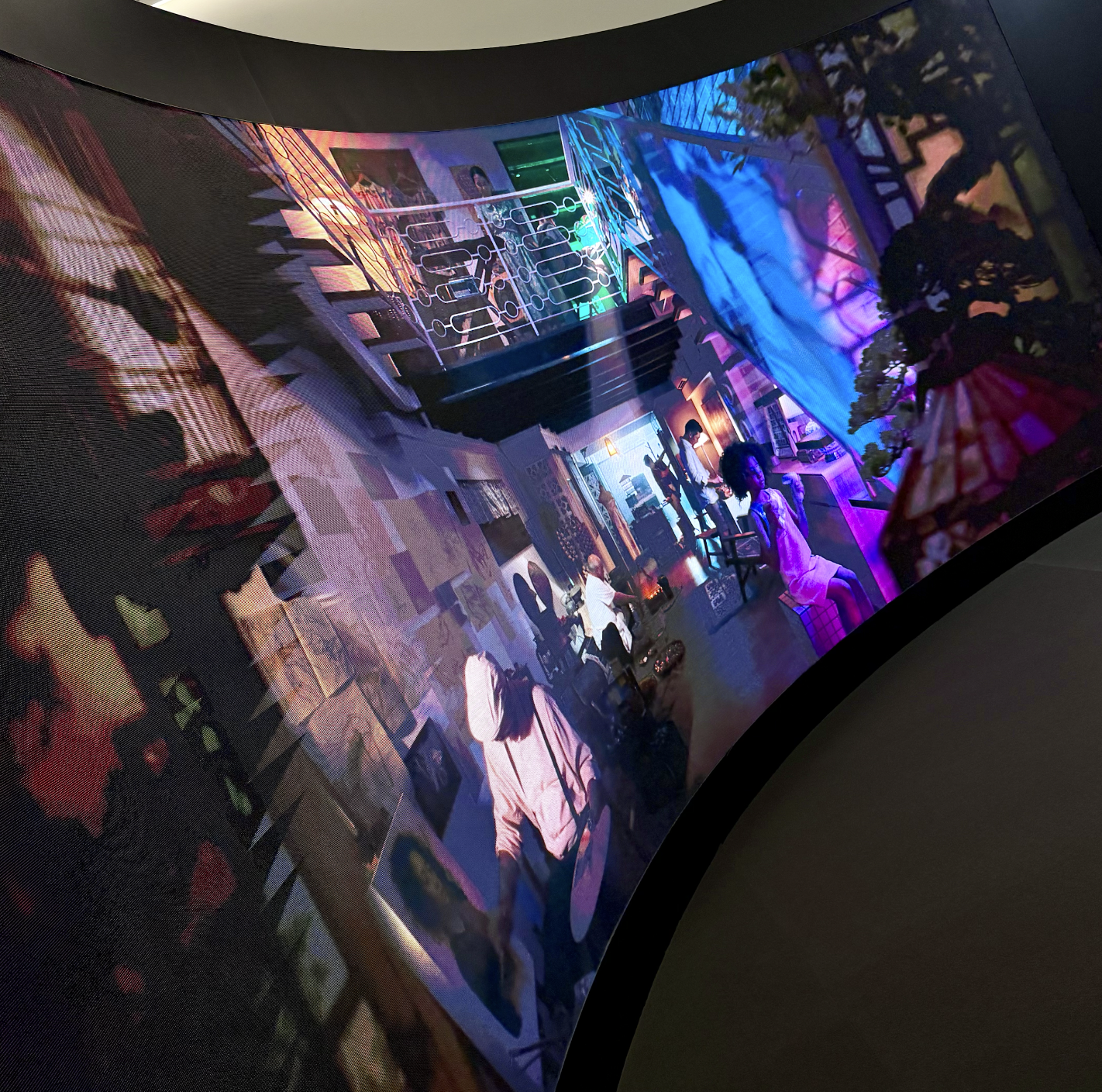 Digital art installation depicting a vibrant, colorful interior scene with people engaging in activities, illuminated by neon and LED lights, with abstract and geometric patterns on the walls and ceiling.