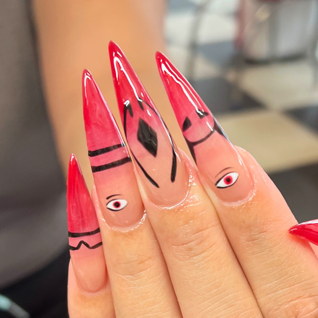 Nail art with pink and black designs resembling eyes and abstract patterns on long, pointed nails.
