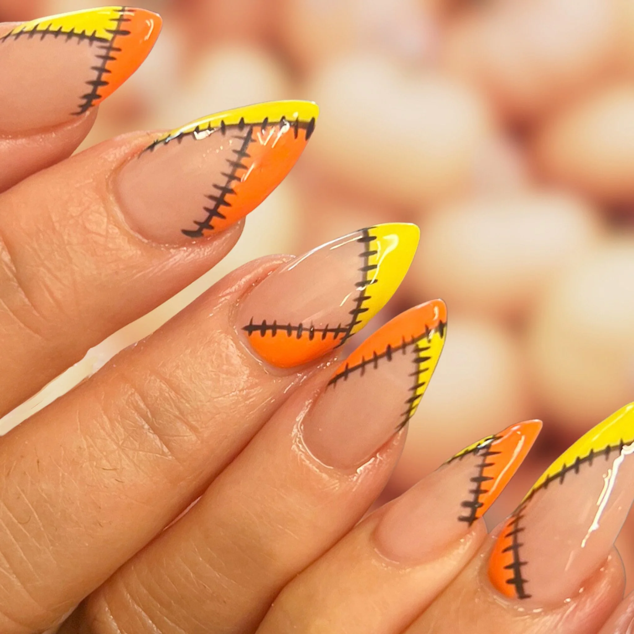 Close-up of a hand with long, decorated nails featuring a colorful line pattern in orange, yellow, and black.