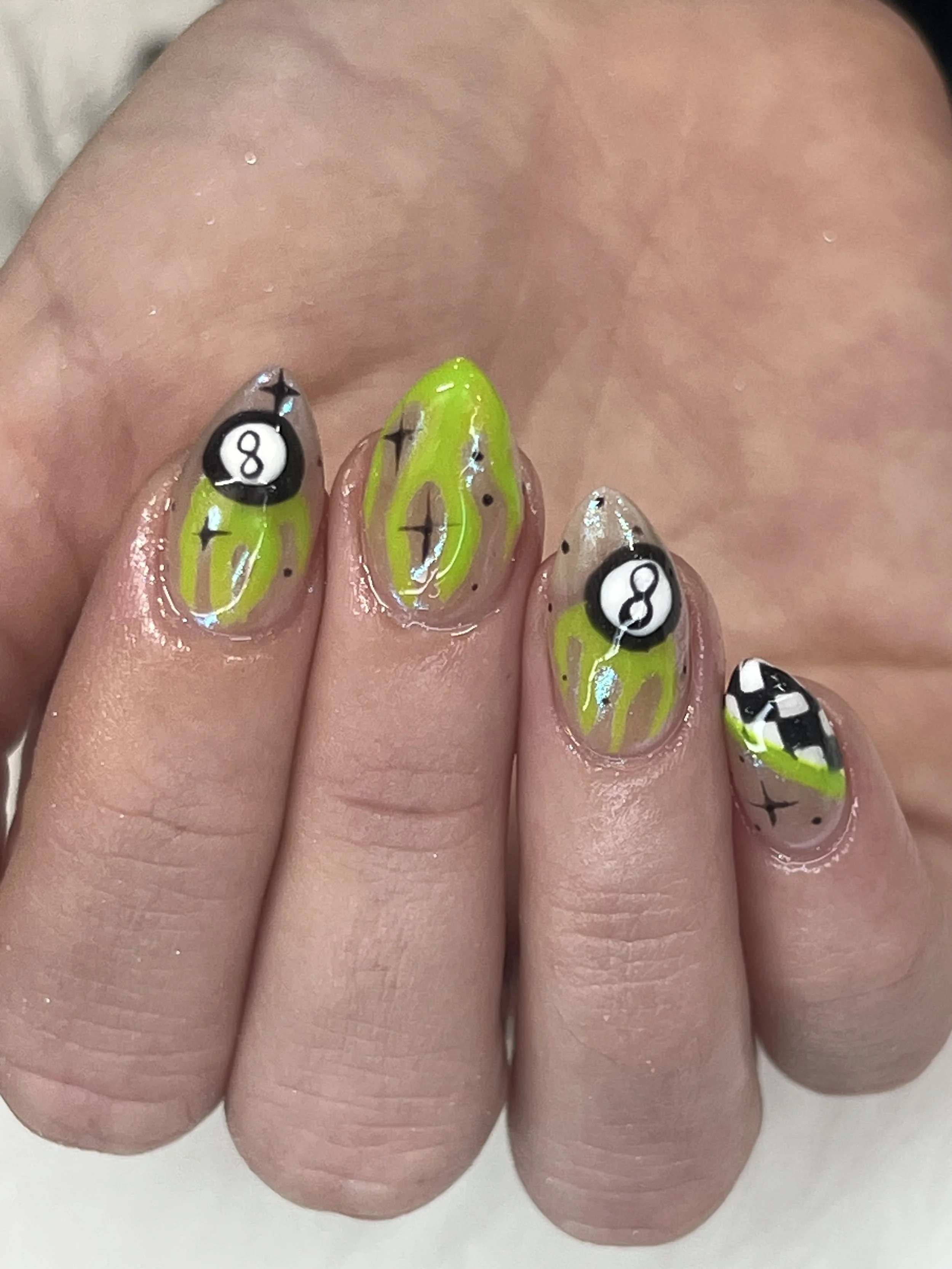 Nail art with a pool and billiards theme, featuring numbers 8 and 8-ball designs, green and black colors, on natural nails.