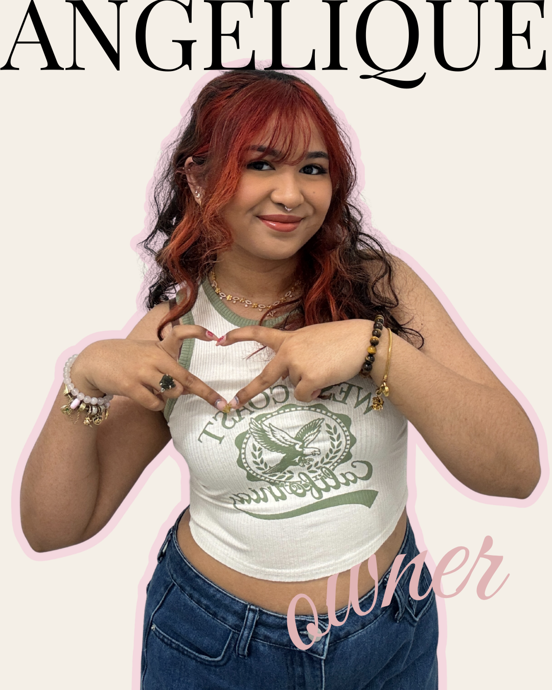 A young woman with red and black hair, wearing a white sleeveless shirt with green accents, jeans, and jewelry, making a heart shape with her hands, smiling at the camera.