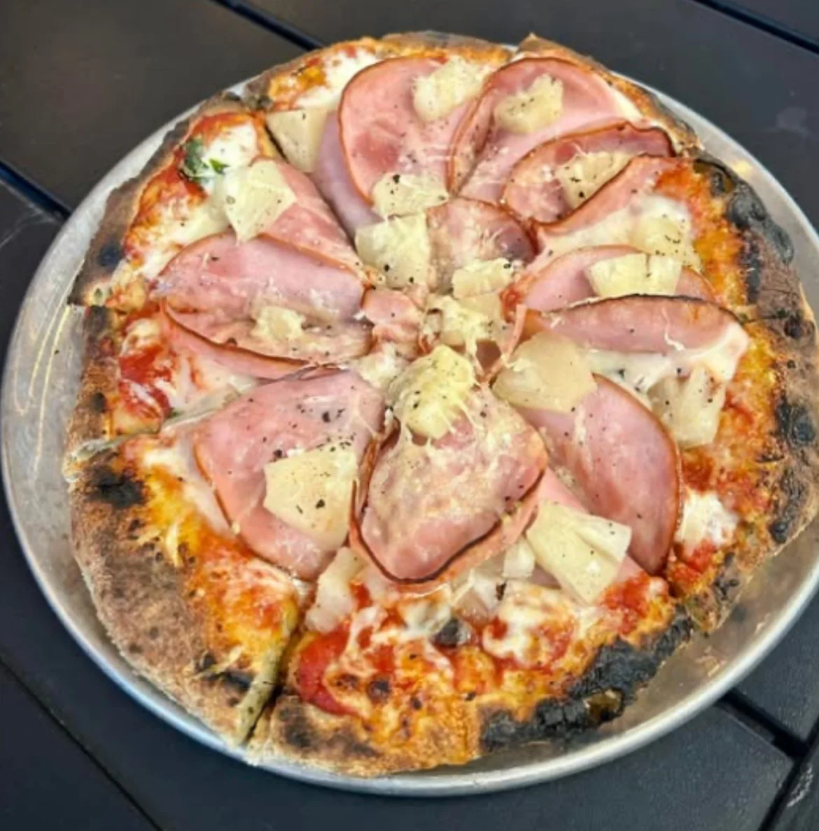 Pizza with ham and pineapple on a metal tray