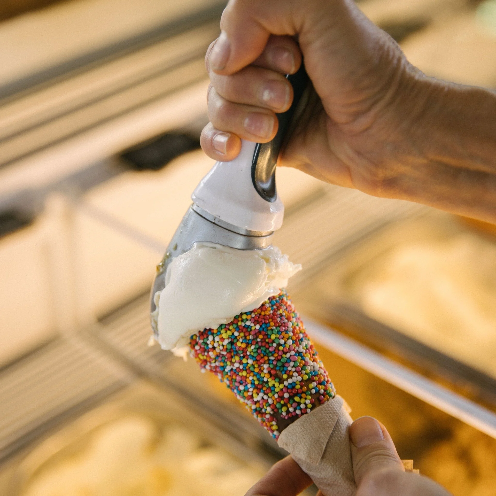 Hand holding a baseball bat with colorful sprinkles at the handle.