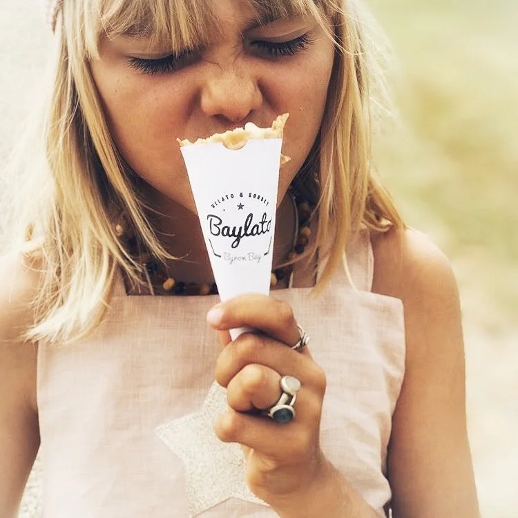 Young woman with blonde hair holding and about to eat an ice cream cone