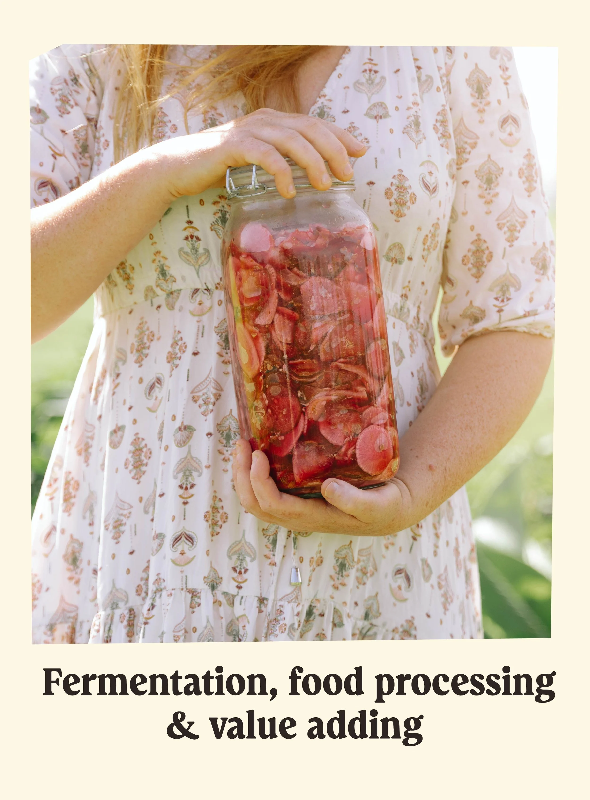 Close-up of a woman holding a glass jar filled with pink and red preserved food, outdoors in natural light.