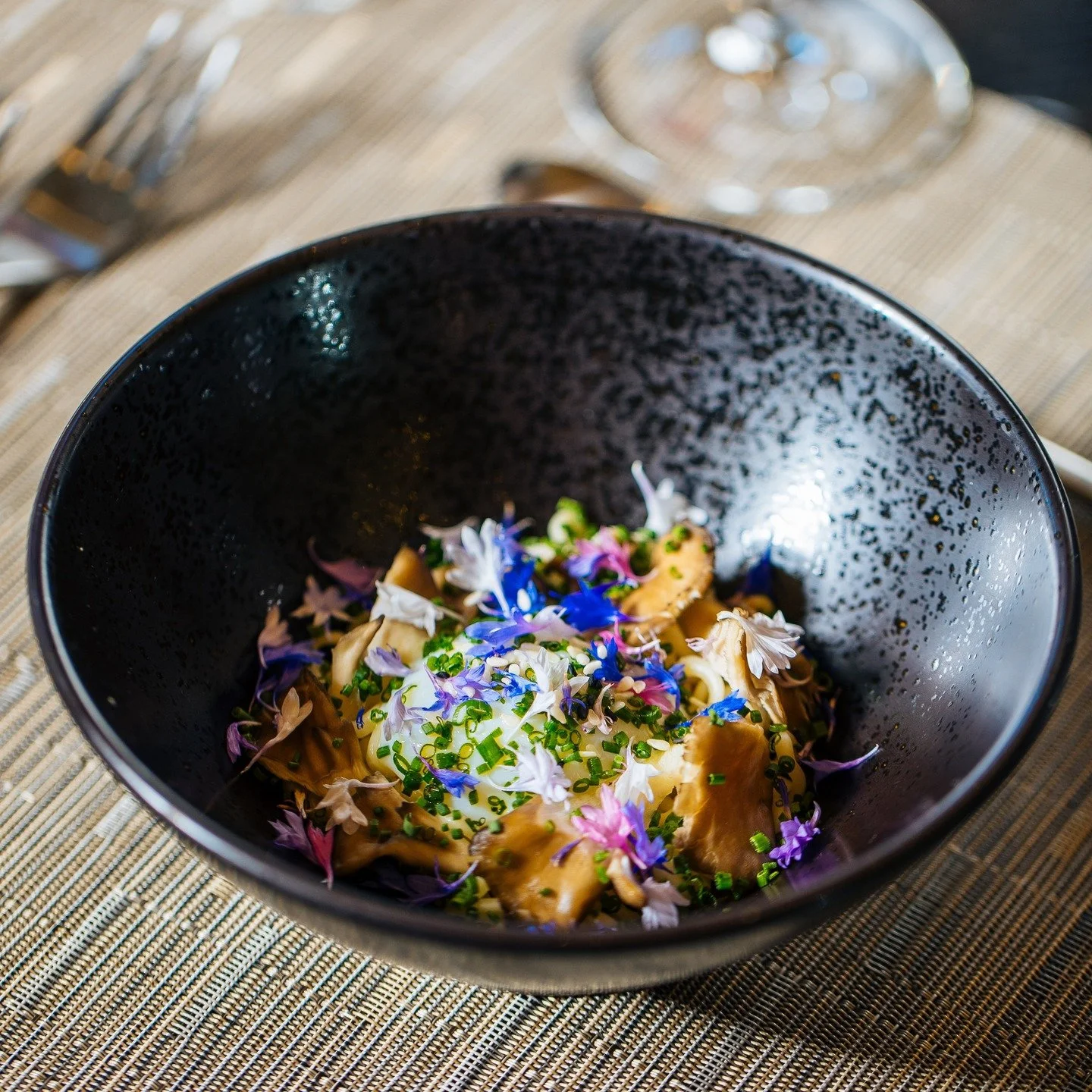 Another signature dish at Five Senses Napa is our Umami Bomb &mdash; a deeply indulgent black garlic ramen. This dish features smoked maitake mushrooms, house-made ramen noodles, and a silky sous-vide Jidori egg, all brought together by our rich blac