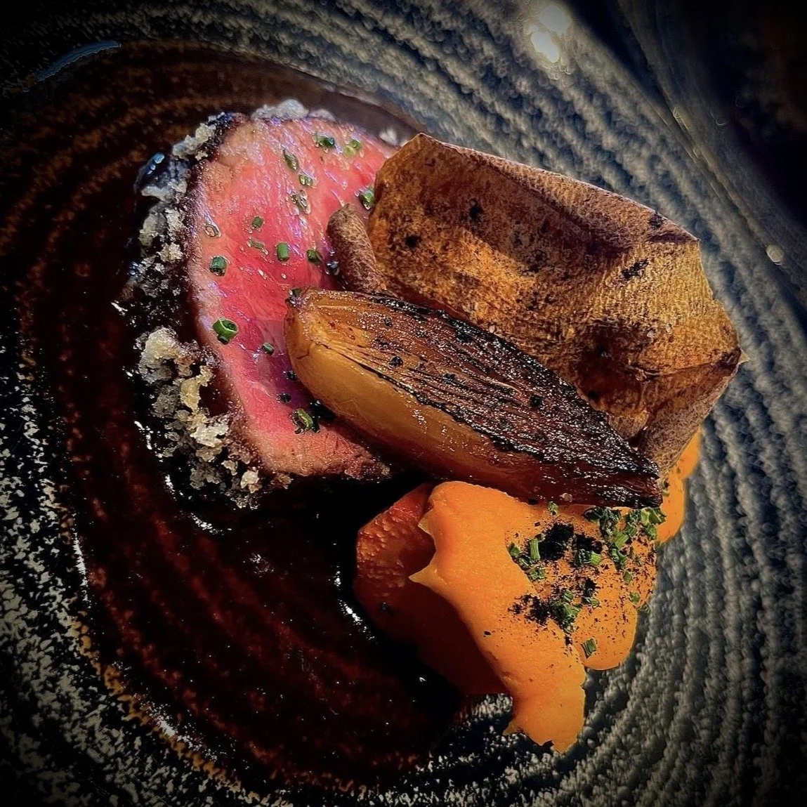 @flannerybeef New York steak, grilled over recycled Cabernet barrel staves and gently finished in a low oven, is brushed continuously with rich demi-glace and, just before slicing, rolled in agedama for an elegant textural crunch. Alongside the steak