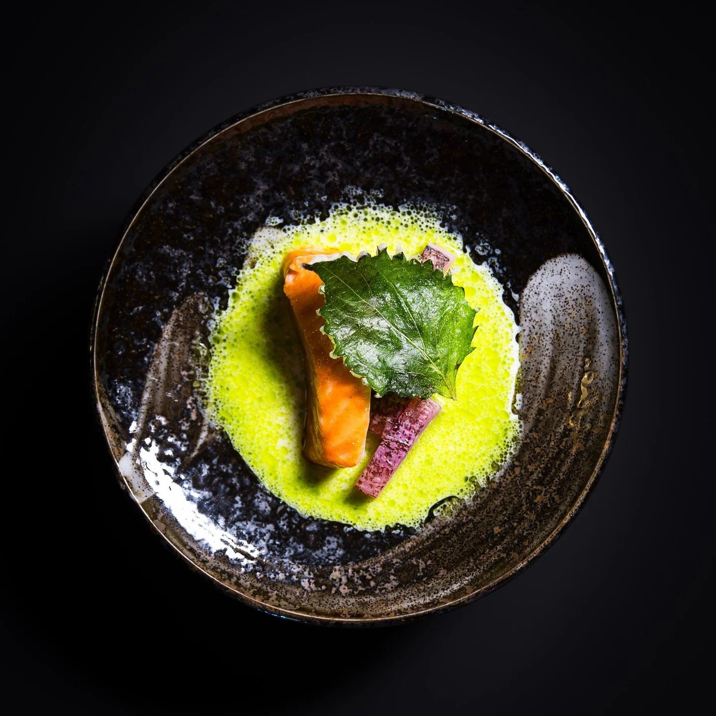 This signature dish from Five Senses Napa features exquisitely pan-seared Ōra King salmon, renowned for its buttery texture and rich marbling. It's delicately placed atop a silky, velvety yogurt-ponzu emulsion, offering a balance of brightness and um