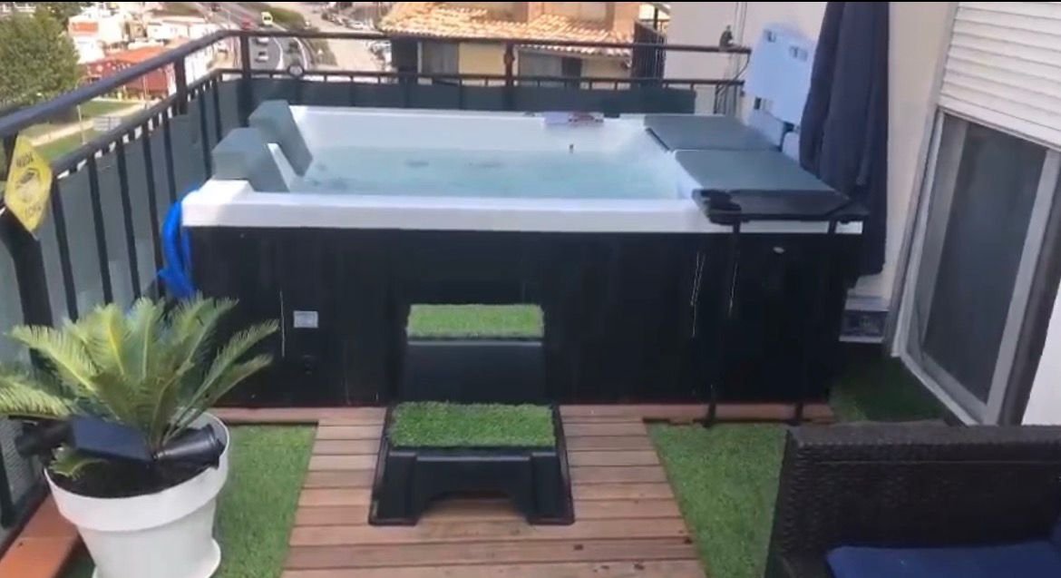 Jacuzzi en una terraza con plantas y muebles.