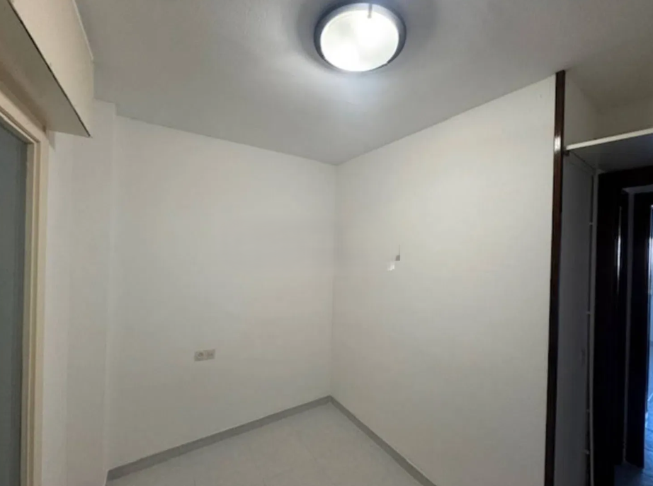 Habitación vacía con paredes blancas, techo con luz redonda y una esquina que tiene una pared de madera con un espacio para closet