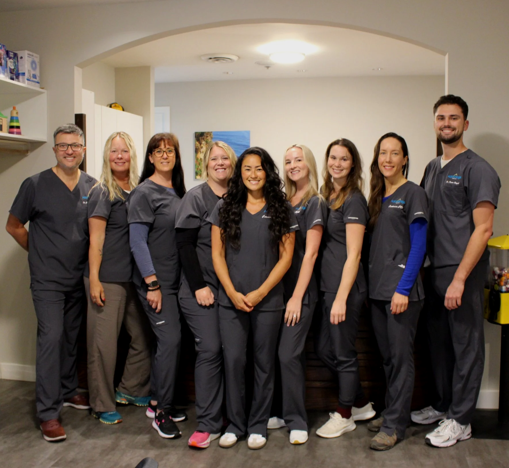 Group of nine healthcare professionals posing together in a clinic environment.
